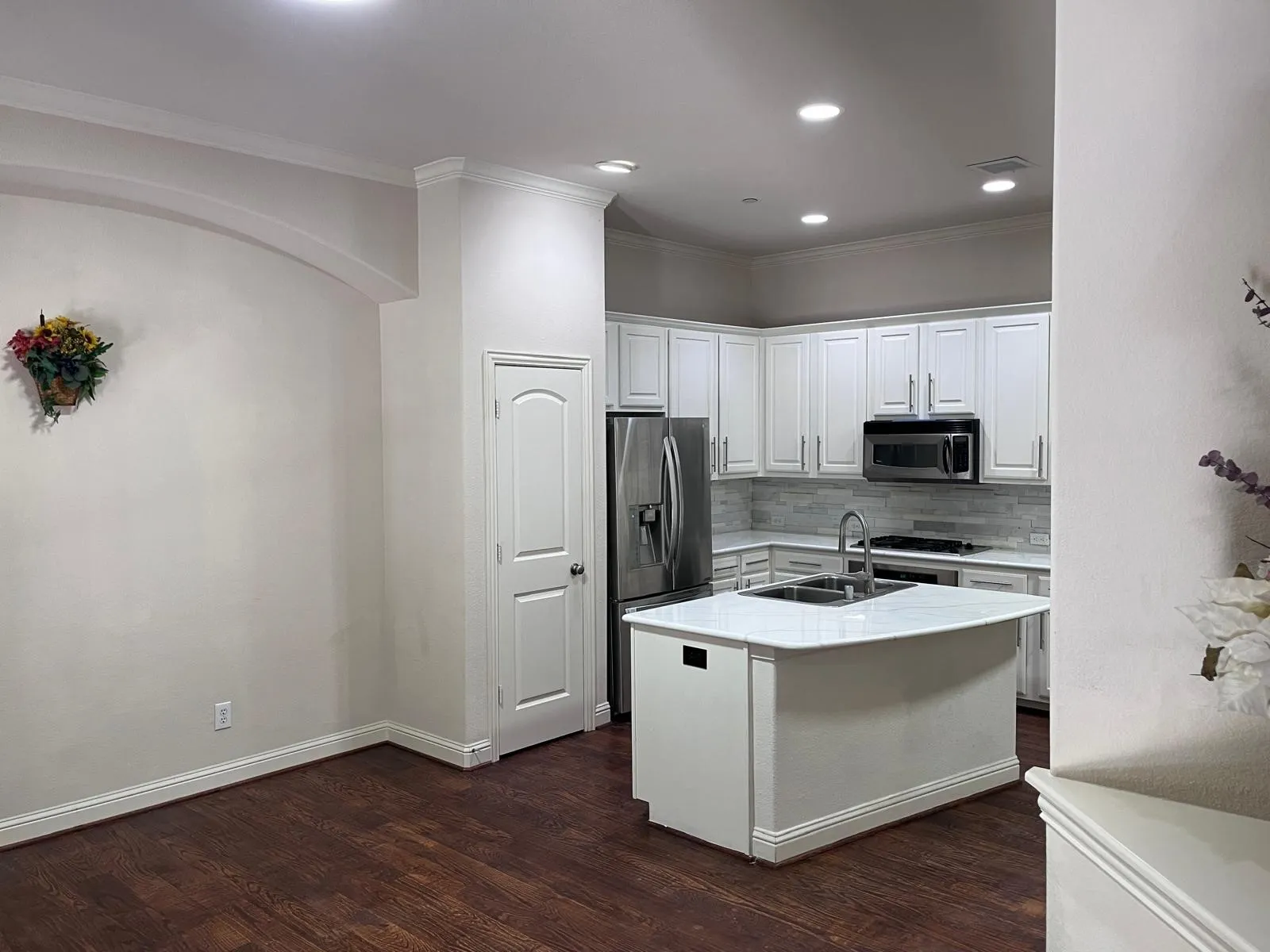 Modern kitchen featuring white cabinetry, stainless steel appliances, a center island with a sink, and wood-finish flooring
