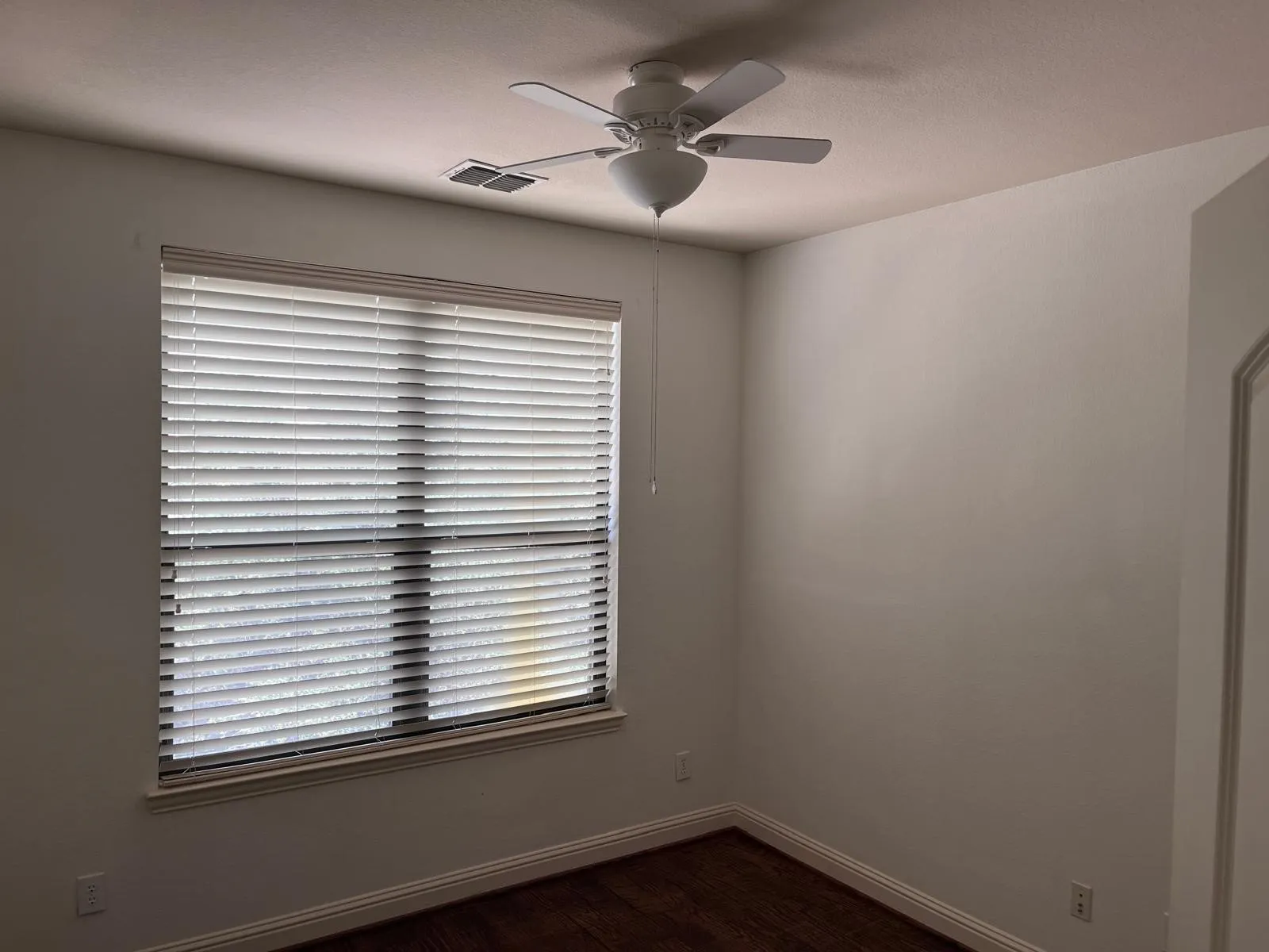 Spacious room featuring a window with white horizontal blinds, a ceiling fan, crown molding, and wood-finish flooring