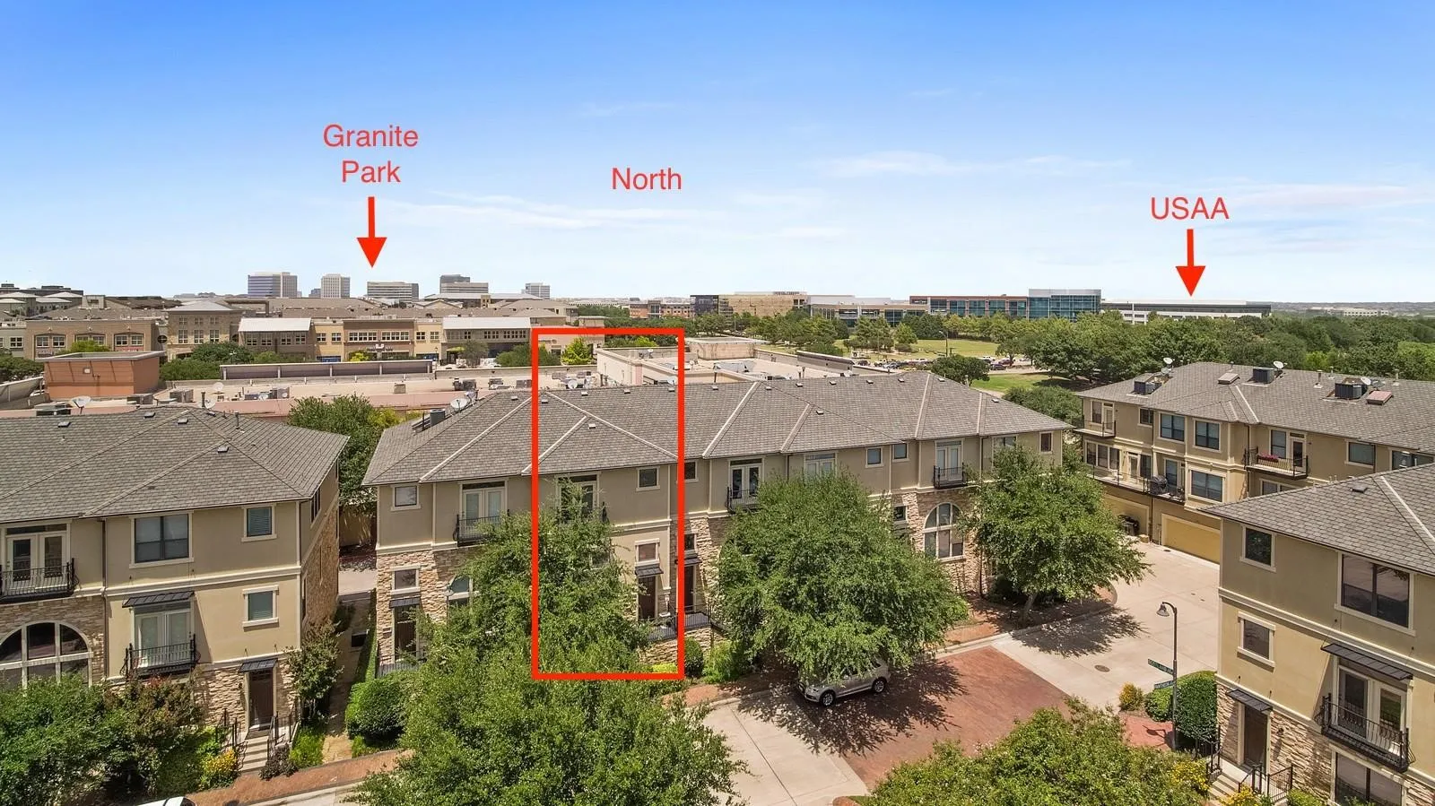 Multi-story townhome featuring a neutral stucco and stone facade, a gabled roofline, and mature landscaping