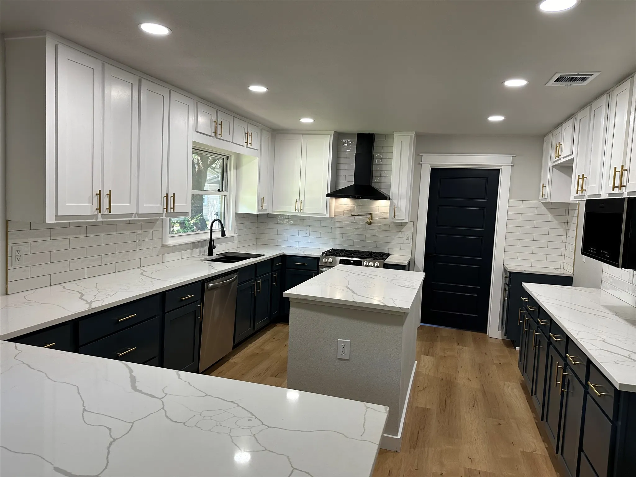 Kitchen with wall chimney exhaust hood, light hardwood / wood-style flooring, white cabinets, and stainless steel dishwasher