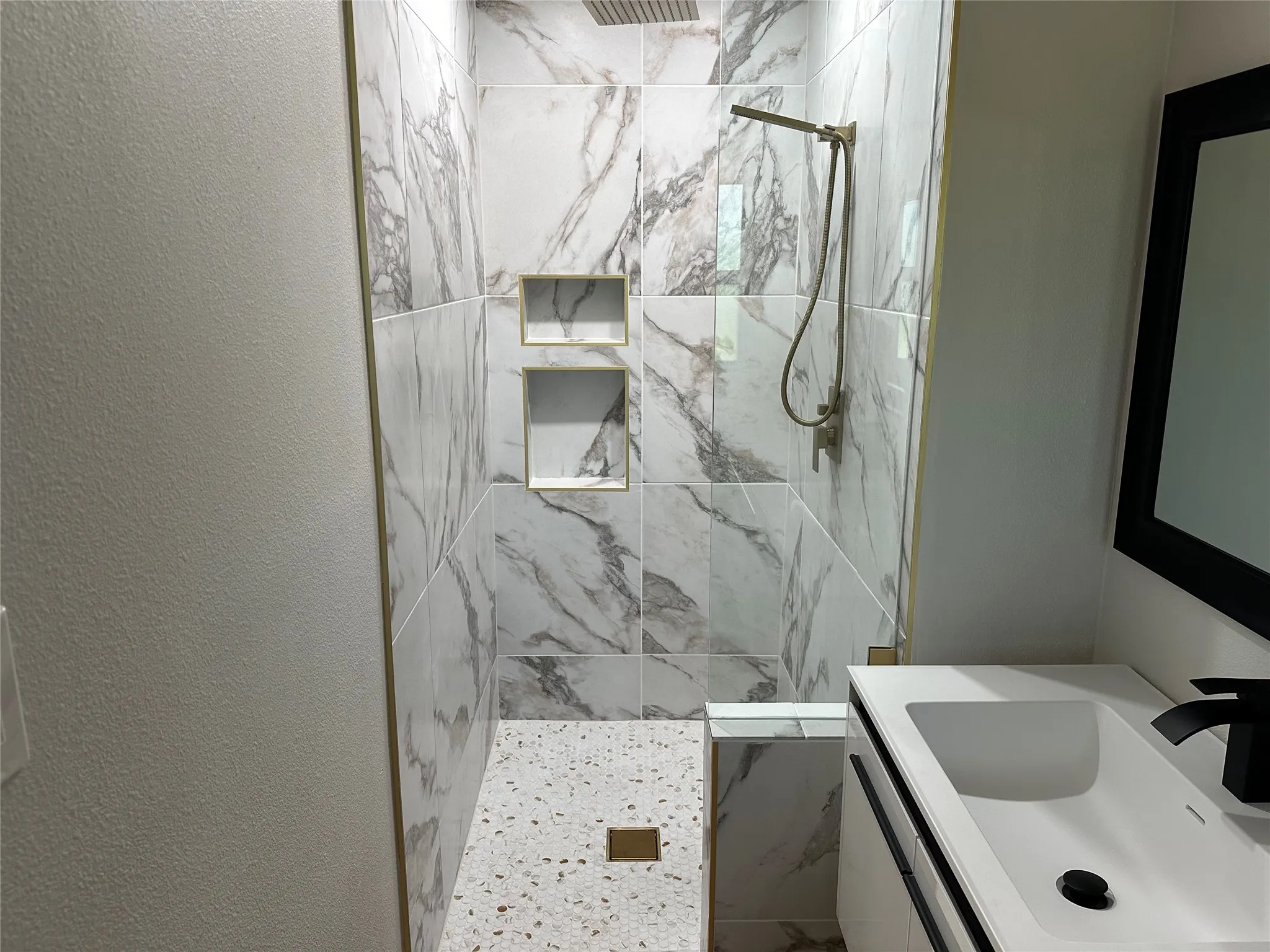 Bathroom with tiled shower, vanity, and tile walls