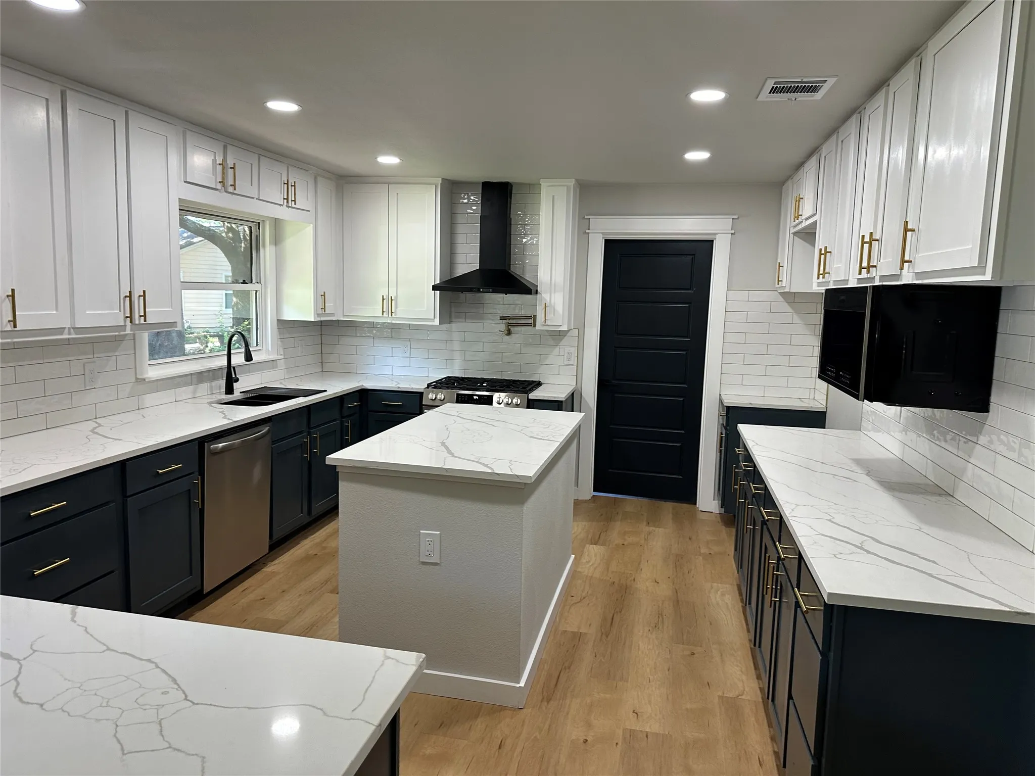 Kitchen with wall chimney exhaust hood, light hardwood / wood-style flooring, tasteful backsplash, and stainless steel dishwasher