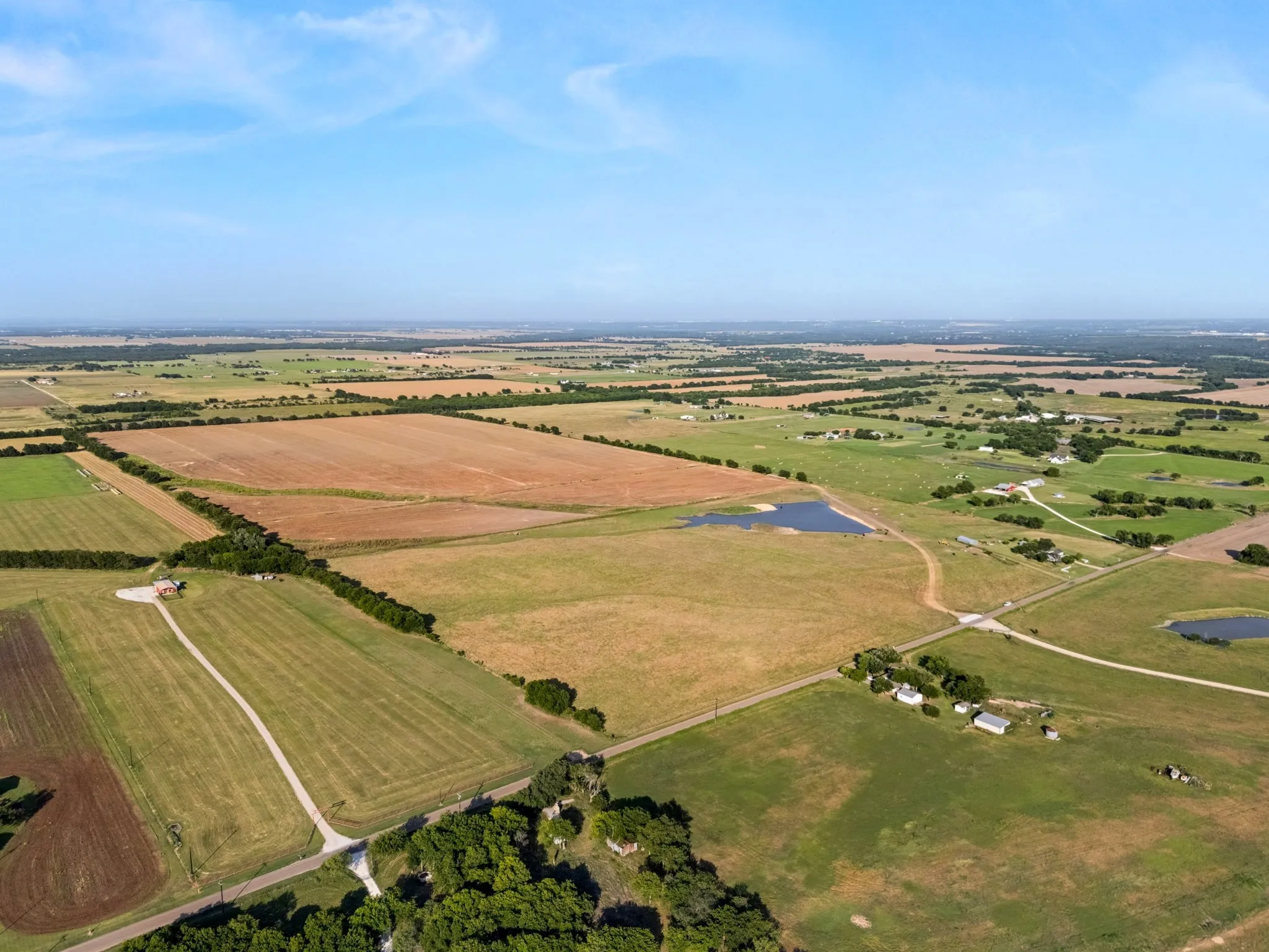 Expansive rural landscape featuring a mix of cultivated fields and green pastures