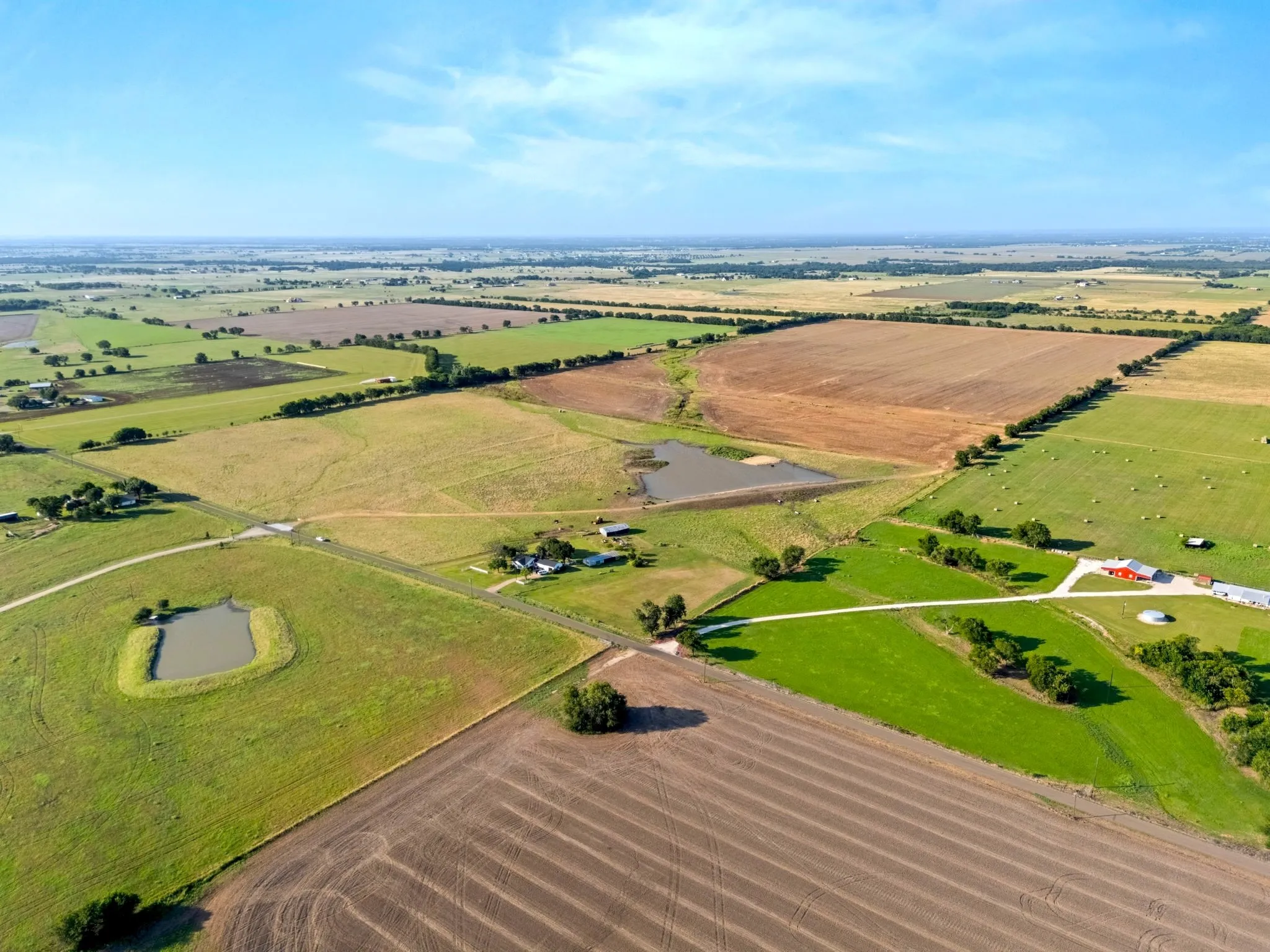 Expansive acreage with diverse agricultural fields and two visible ponds