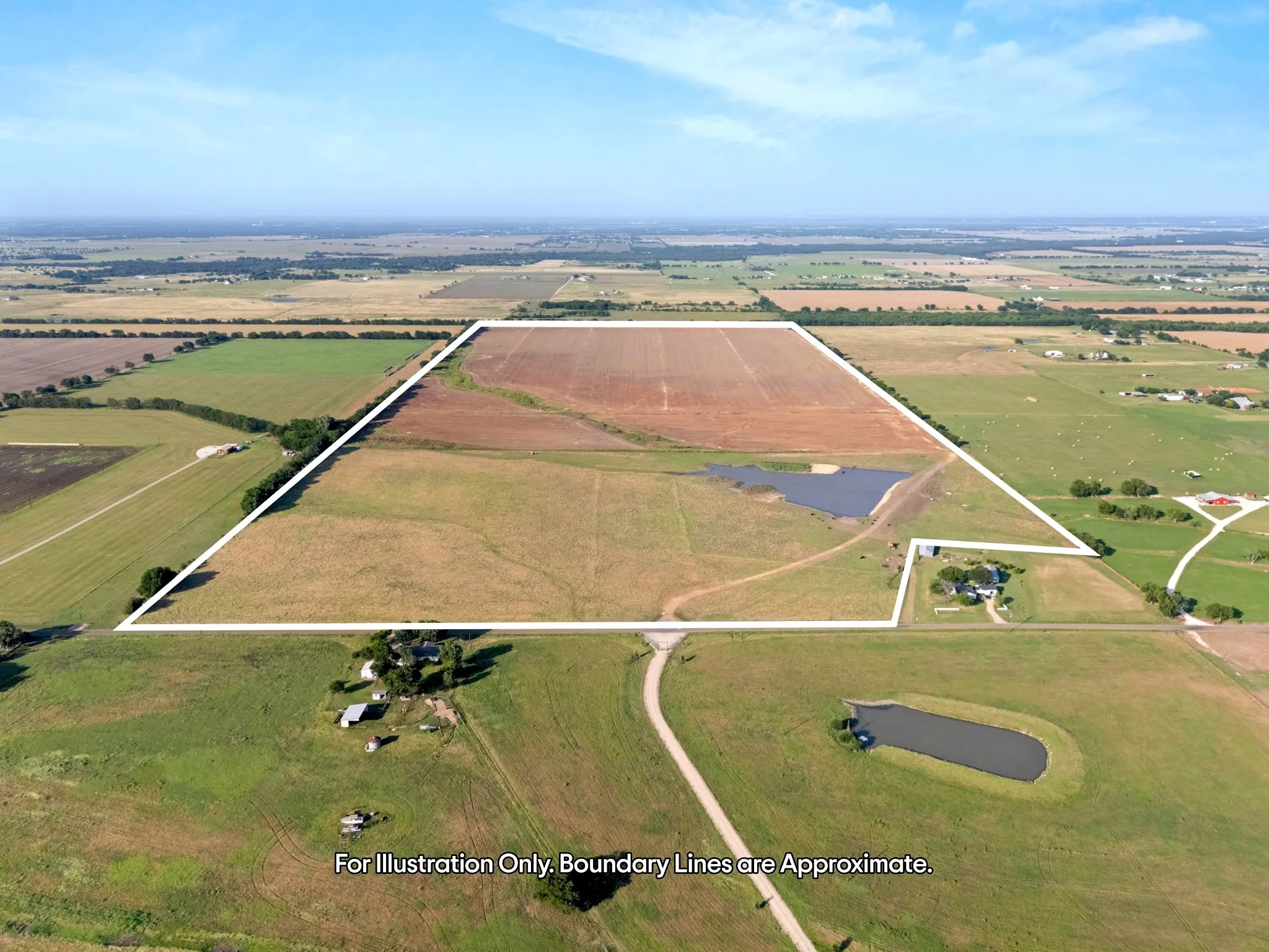 Expansive land parcel featuring open fields, an established pond, and existing structures