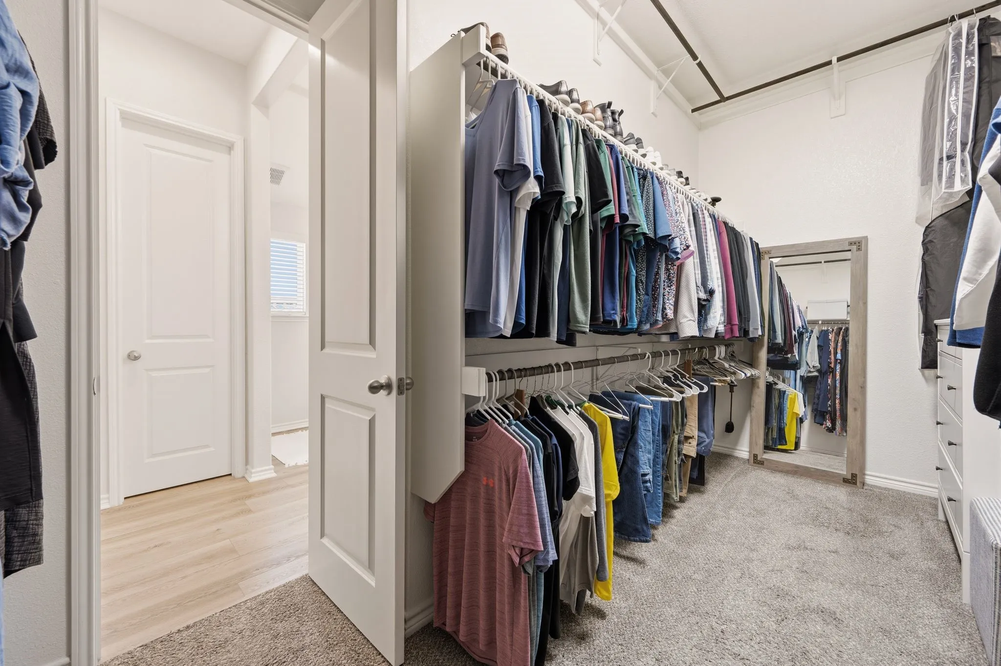 Walk-in closet featuring extensive built-in shelving, multiple hanging rods, and an integrated full-length mirror