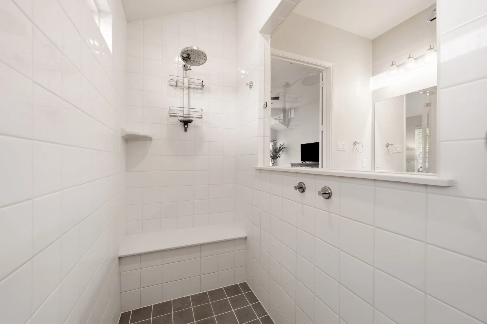 Tiled shower enclosure featuring a fixed showerhead, built-in bench, and an integrated shelf