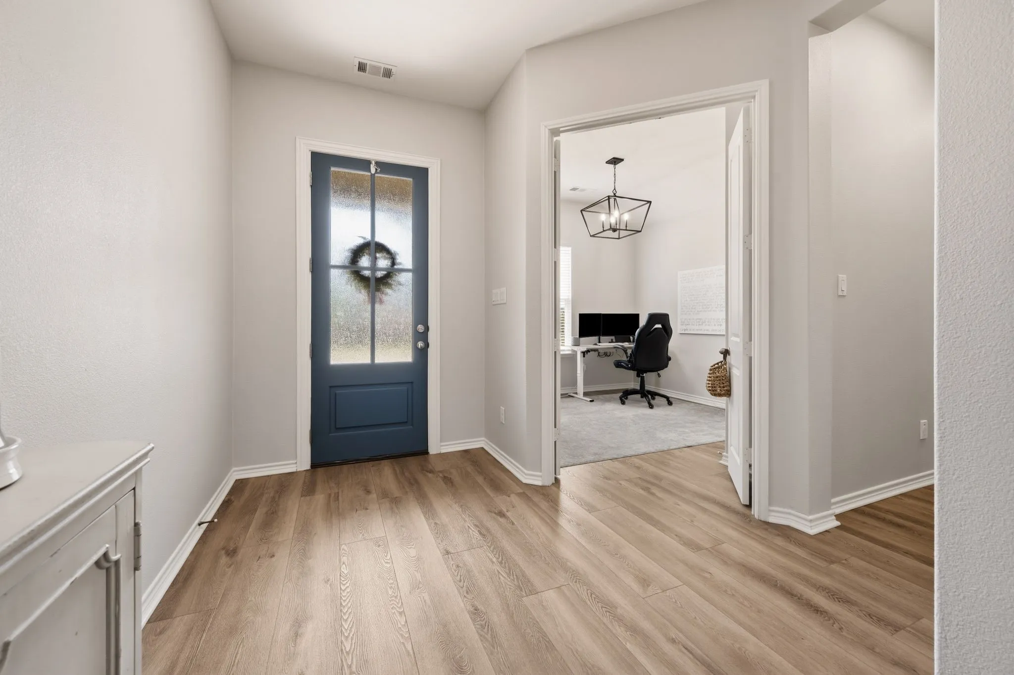 Entryway featuring updated high quality LVP  flooring, a vibrant blue front door with frosted glass panels, and great natural light that makes for an amazing space to welcome all your friends and family!