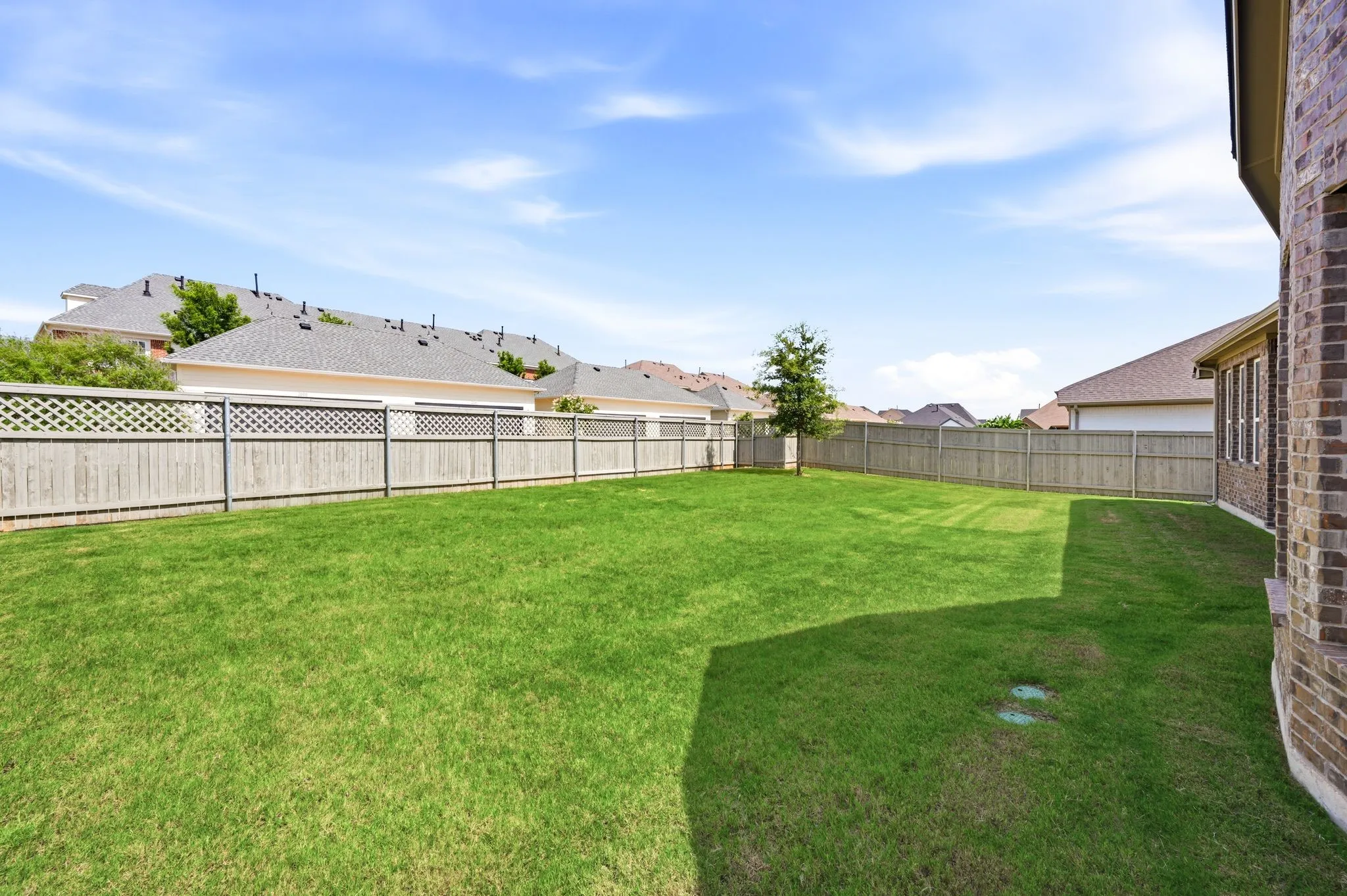Expansive backyard featuring a lush lawn and perimeter wood fencing