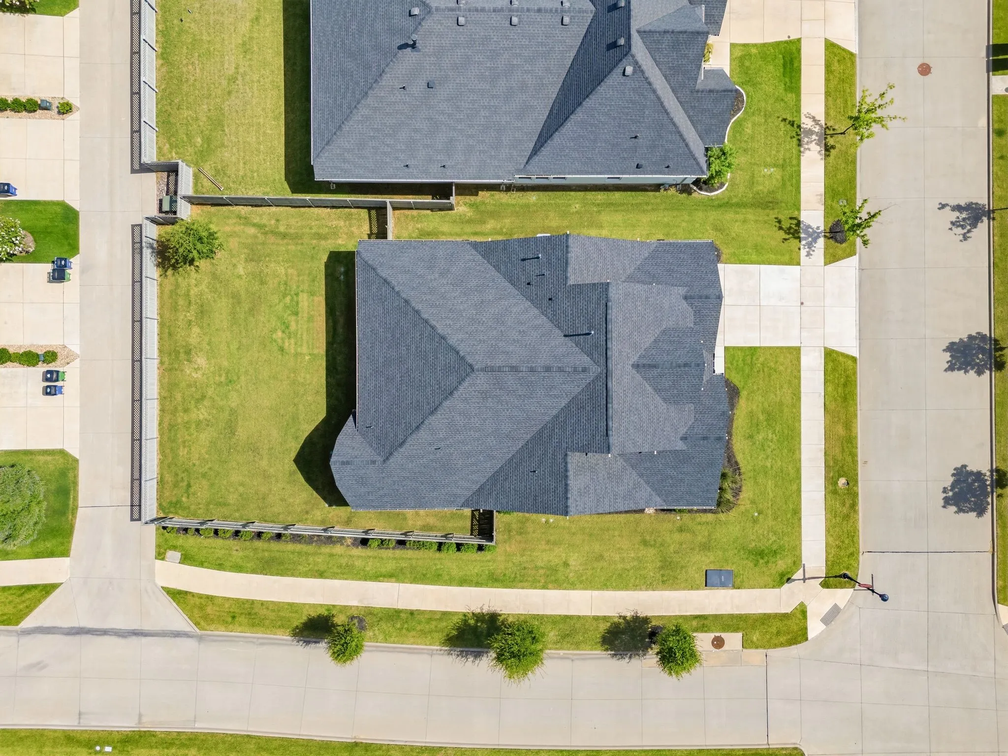 Property featuring a dark shingle roof, expansive green lawn, and concrete driveway