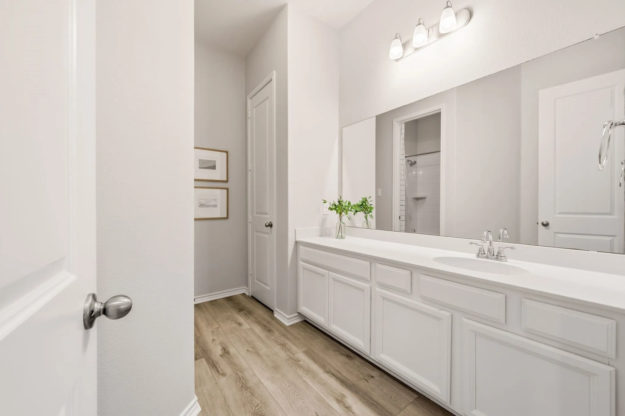 Bathroom featuring an extended vanity with dual sinks, white cabinetry, and a full-width mirror