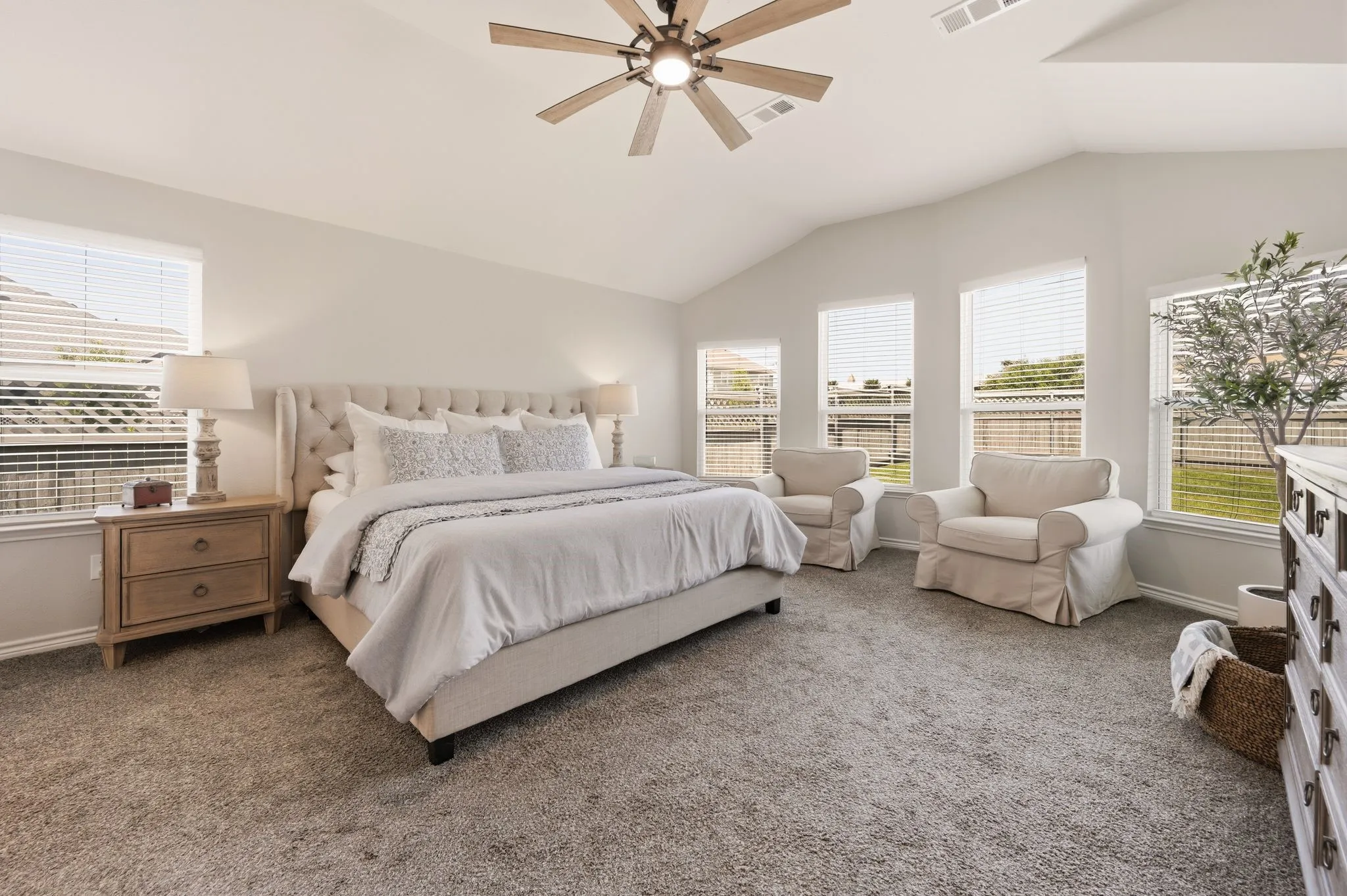 Vaulted ceiling bedroom with a ceiling fan light fixture and carpet flooring