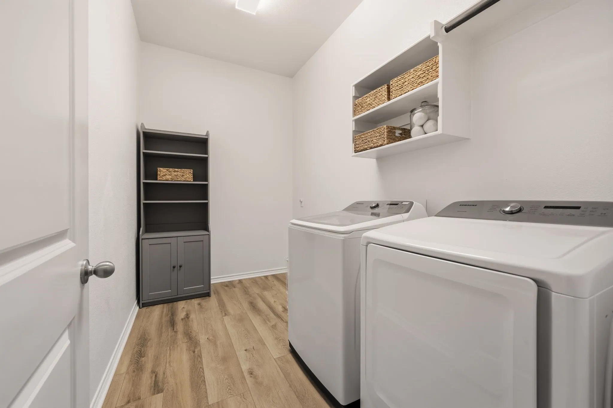 Dedicated utility space featuring wood-finish flooring and white walls