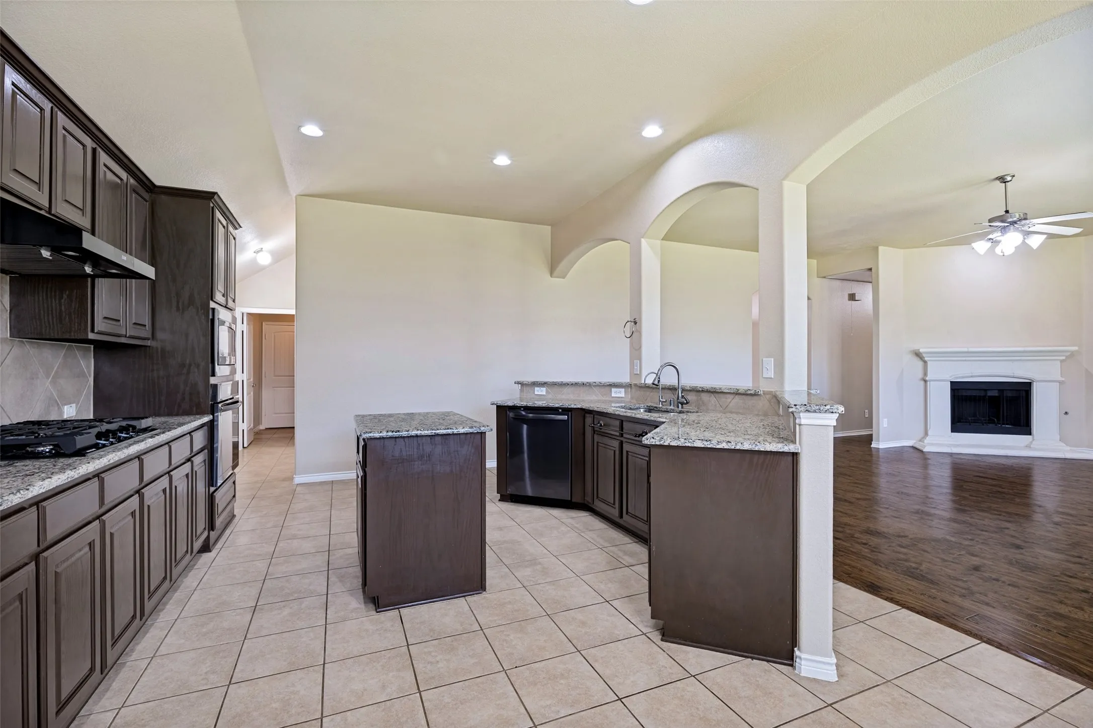 Kitchen featuring dark wood cabinetry, granite countertops, and tile flooring