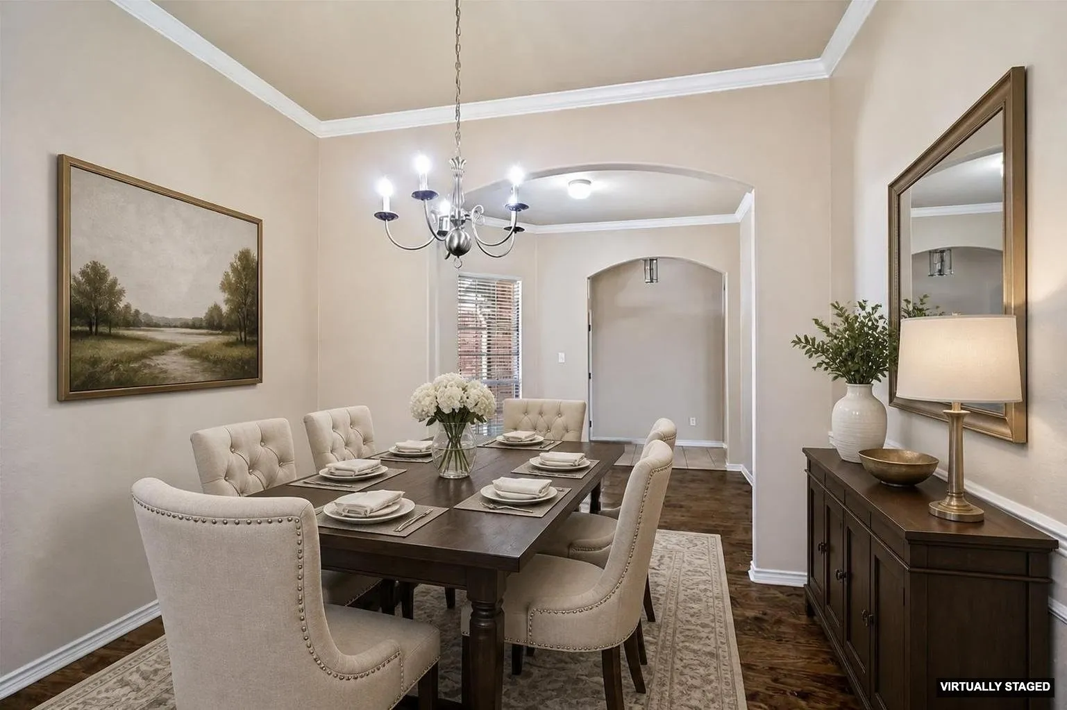 Dining area featuring wood-finish flooring, Staged Dining with crown molding, and an arched doorway