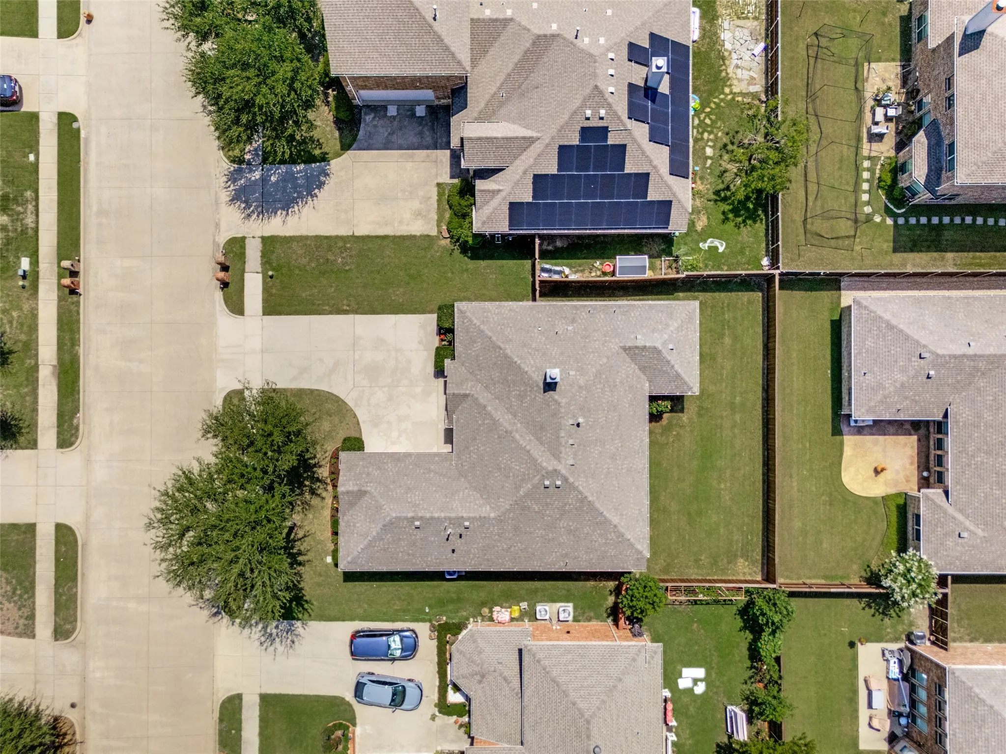 Property featuring a gray shingle roof, concrete driveway, and expansive green lawn