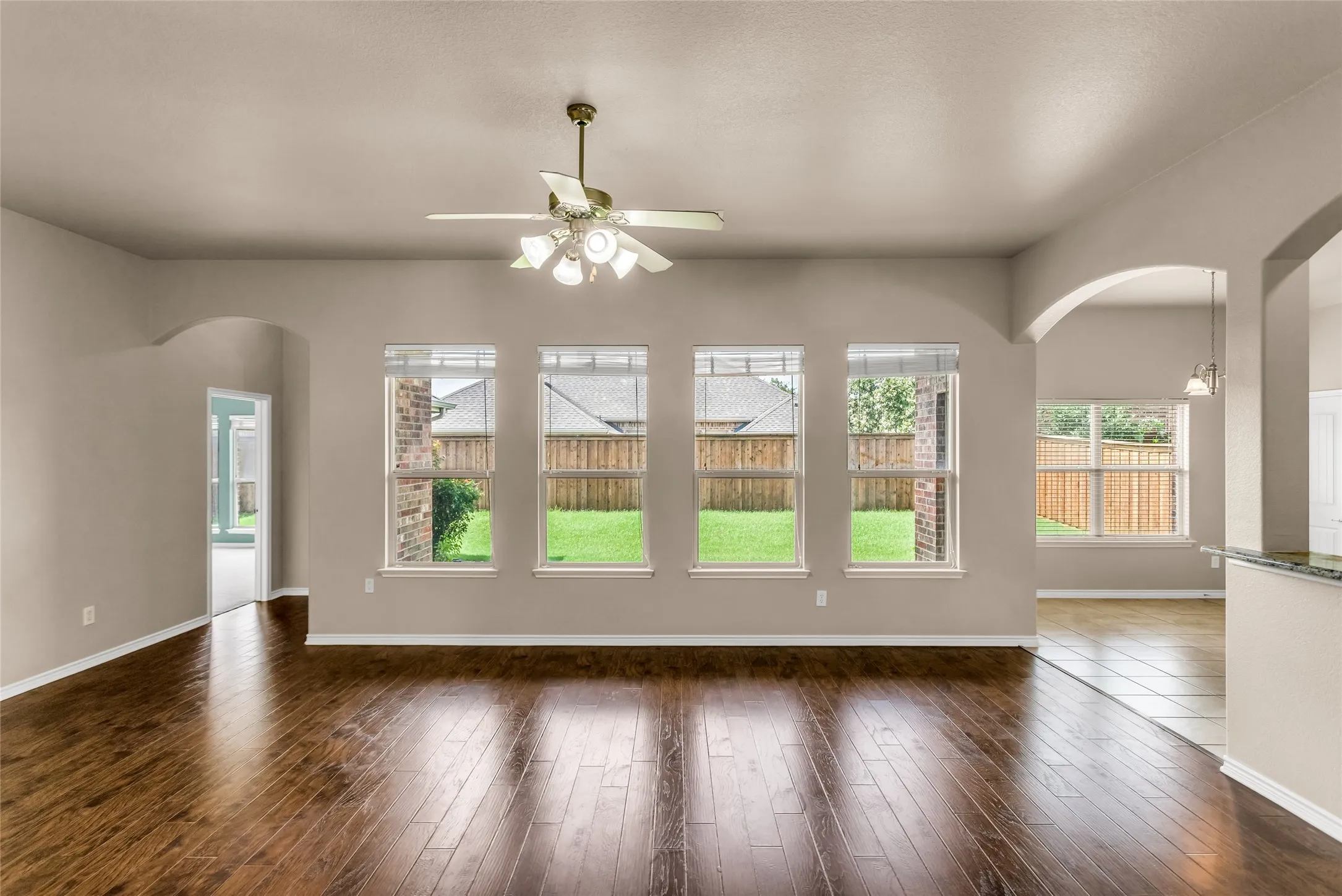 Living room with arched walkways, ceiling fan, and wood finished floors