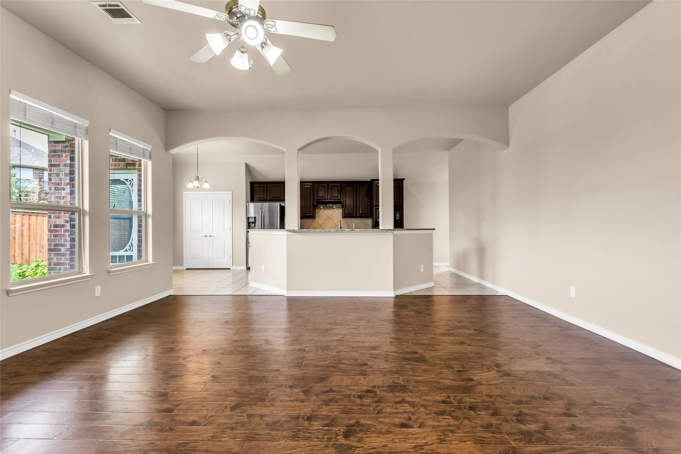 Unfurnished living room featuring light wood-style floors, ceiling fan, and arched walkways