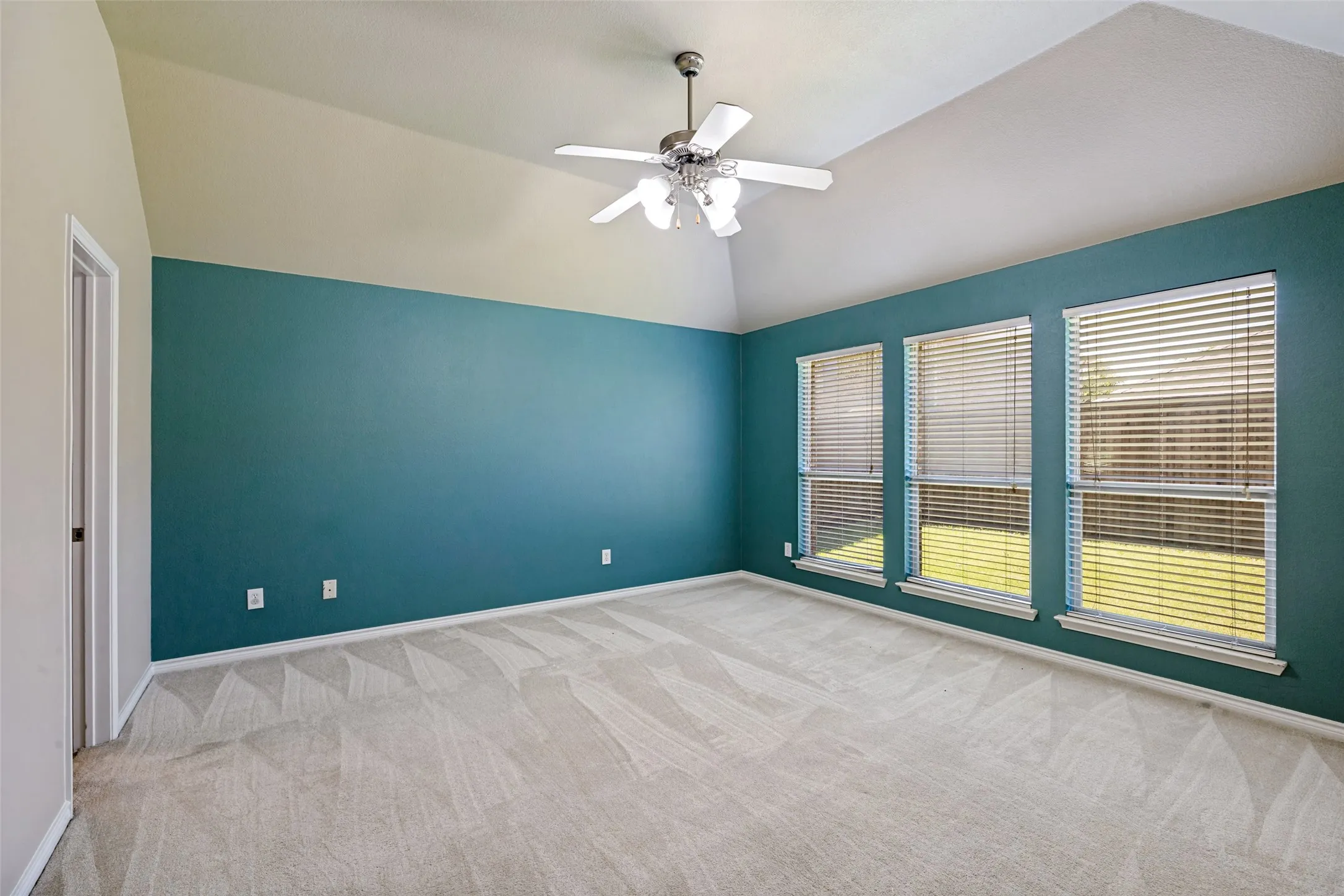 Spacious room featuring vaulted ceilings and a ceiling fan with light fixture