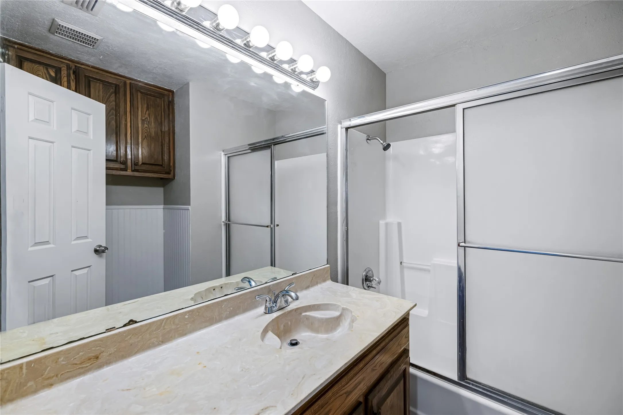 Bathroom featuring vanity and enclosed tub / shower combo