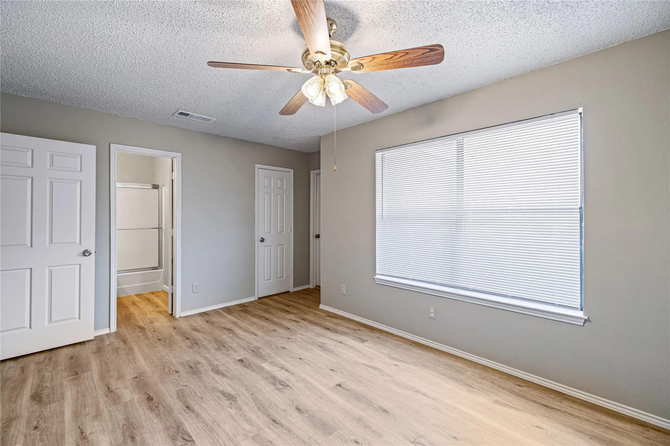 Unfurnished bedroom featuring light wood finished floors, visible vents, baseboards, ensuite bathroom