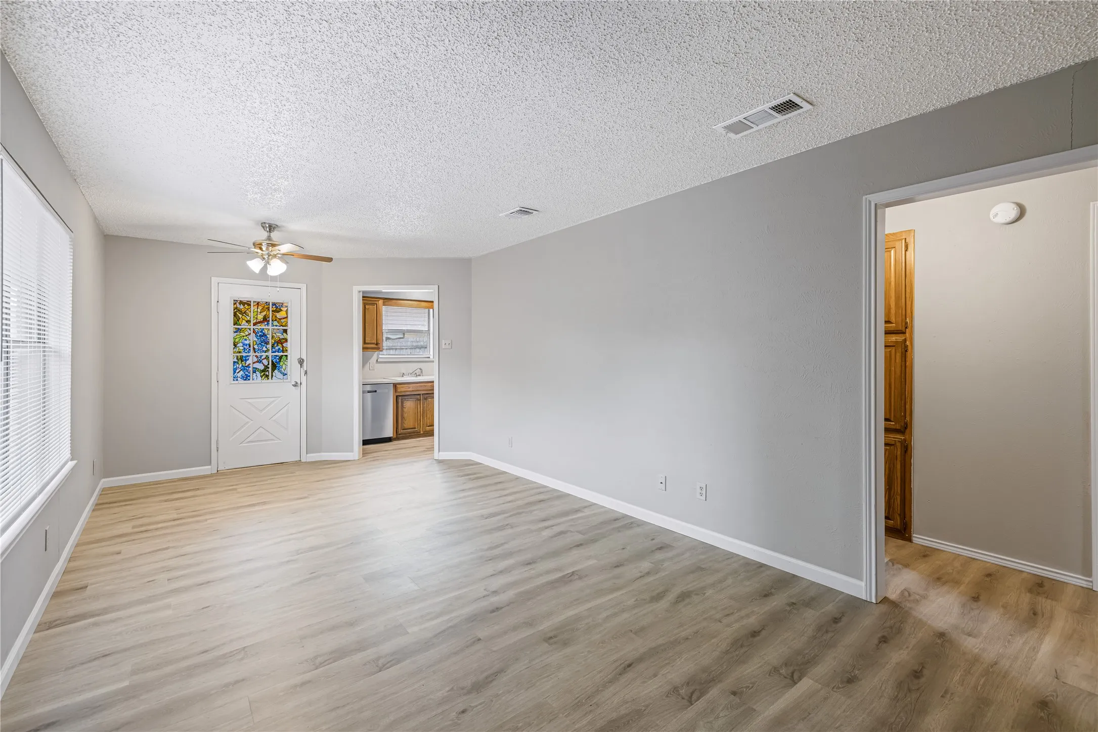Unfurnished living room featuring, baseboards, ceiling fan, and light wood-style flooring
