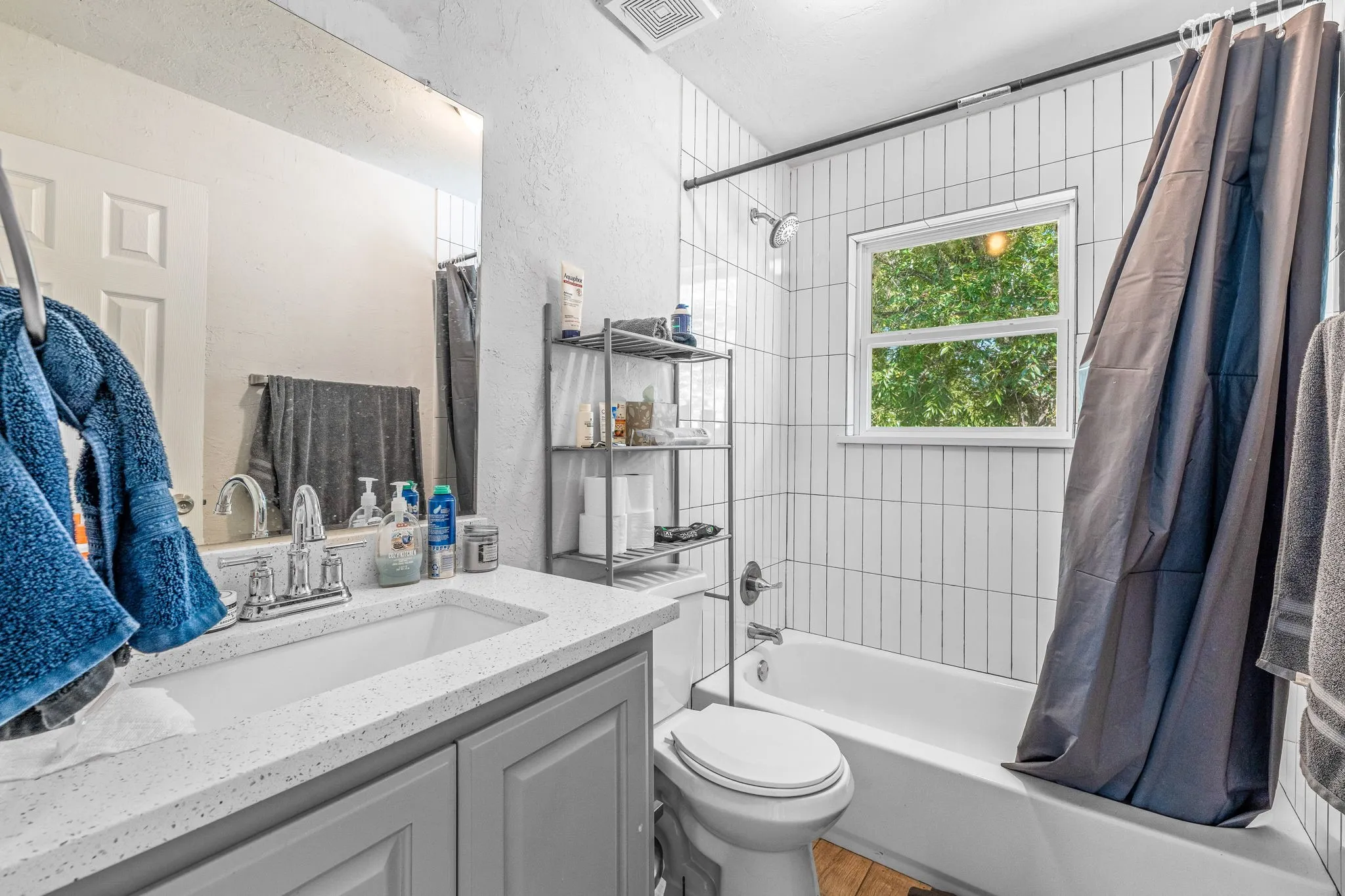 Bathroom featuring a textured wall, shower / tub combo with curtain, and vanity