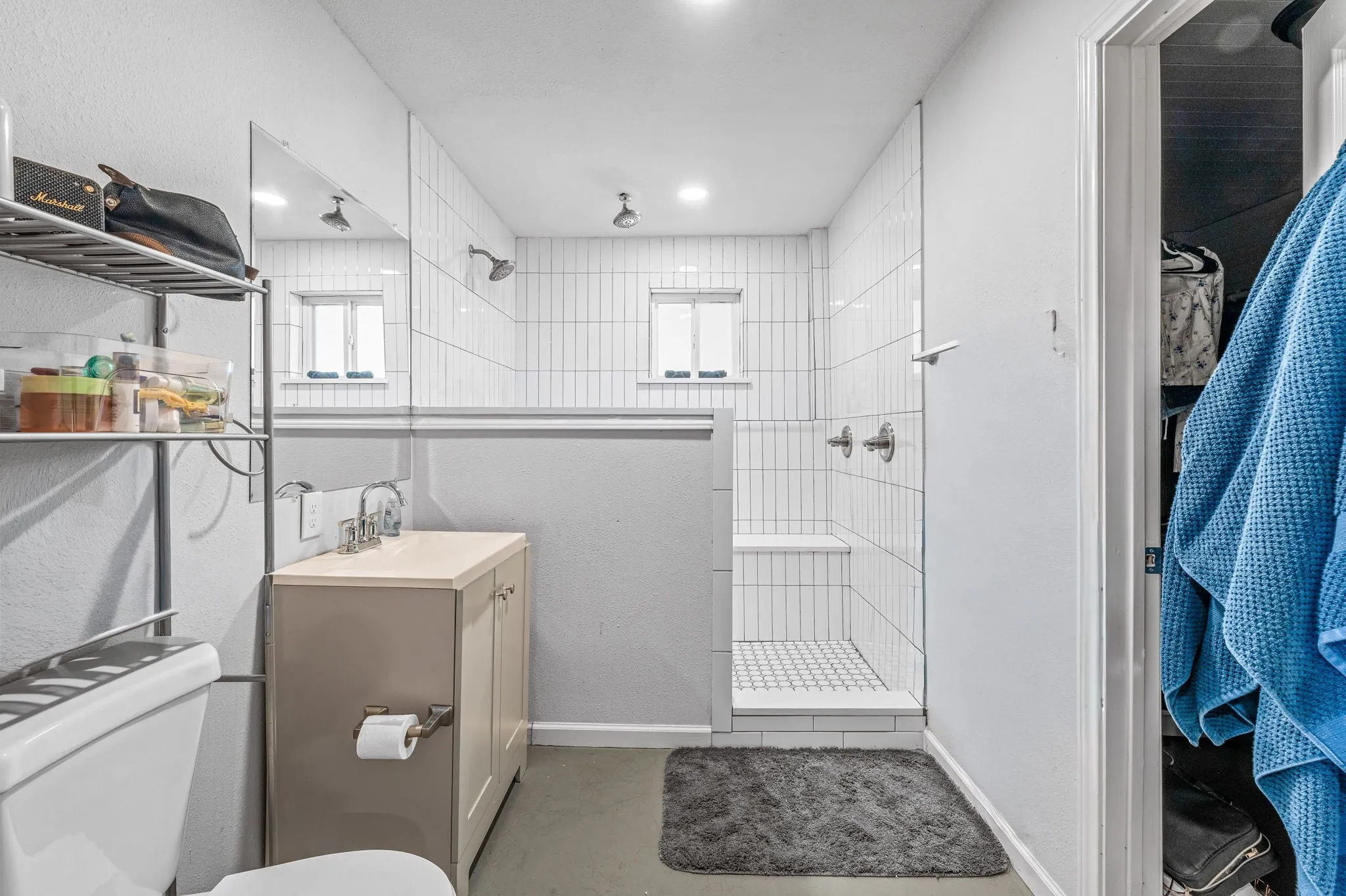Bathroom featuring a walk in shower, vanity, concrete flooring, a closet, and recessed lighting