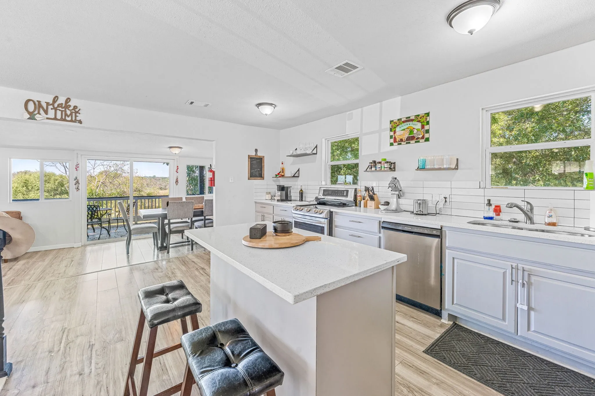 Kitchen featuring light wood-style flooring, tasteful backsplash, light stone counters, stainless steel appliances, and a kitchen breakfast bar