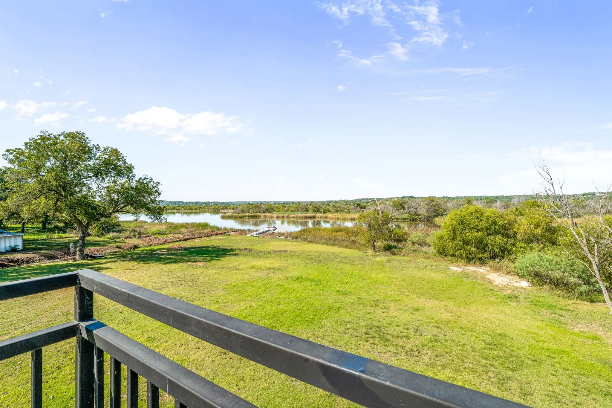 View of green lawn with a water view and a balcony
