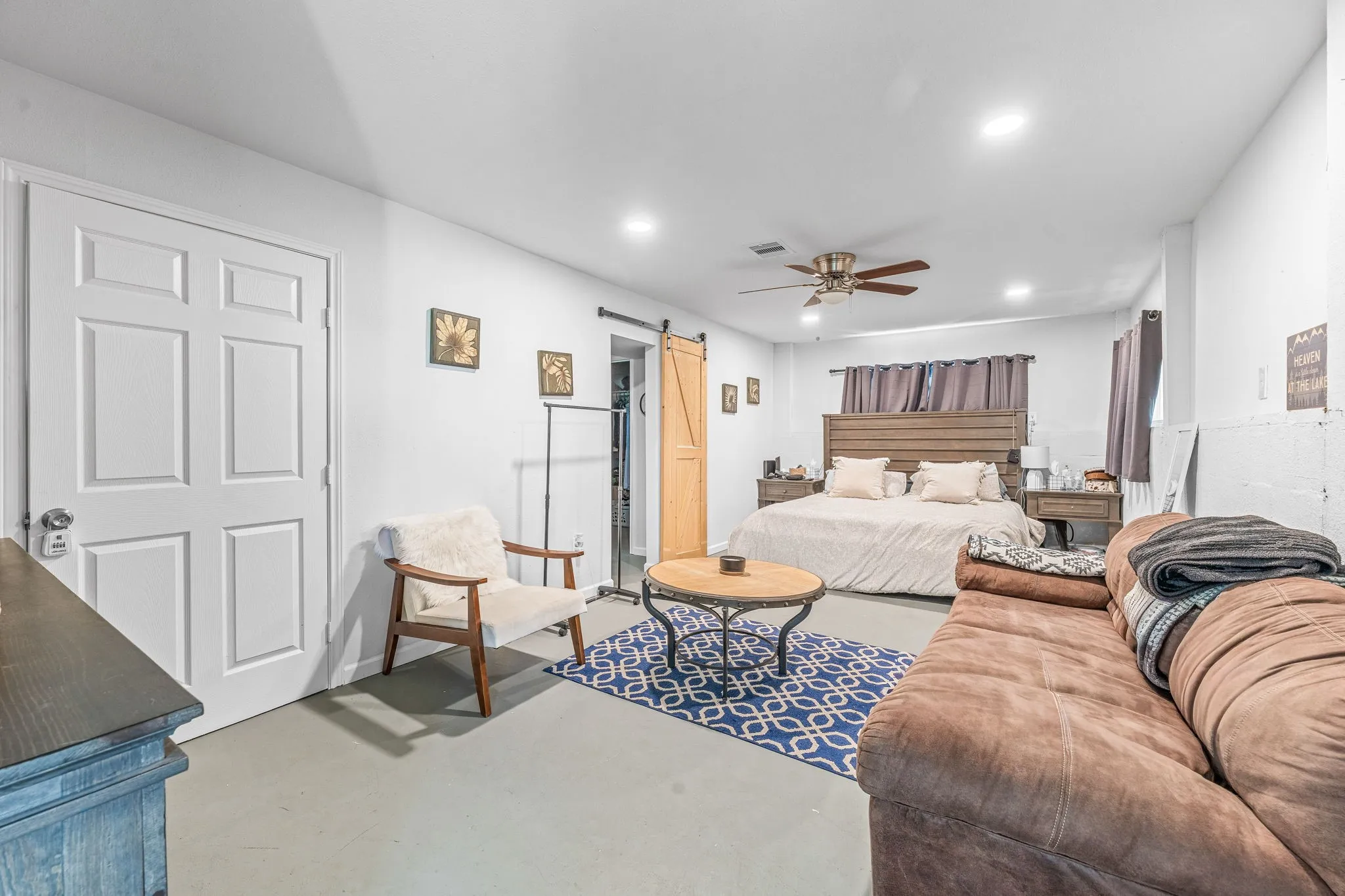 Bedroom with a barn door, finished concrete flooring, a ceiling fan, and recessed lighting