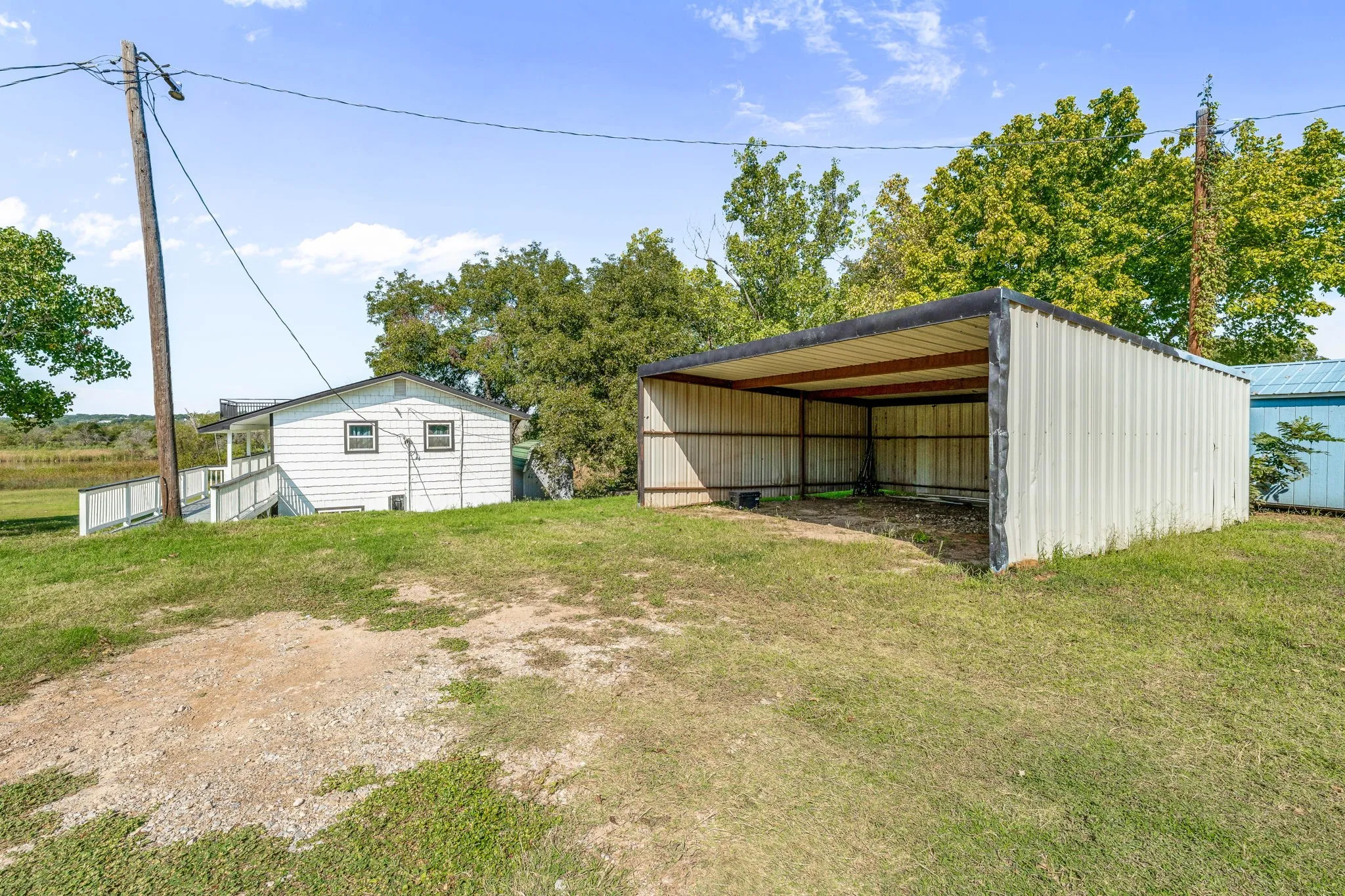 View of green lawn featuring a carport, an outbuilding, and an outdoor structure