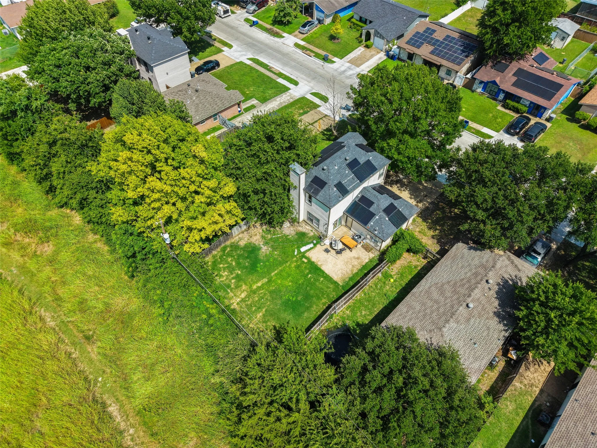 Expansive residential property featuring a gray shingle roof, solar panels, and a large grassy yard