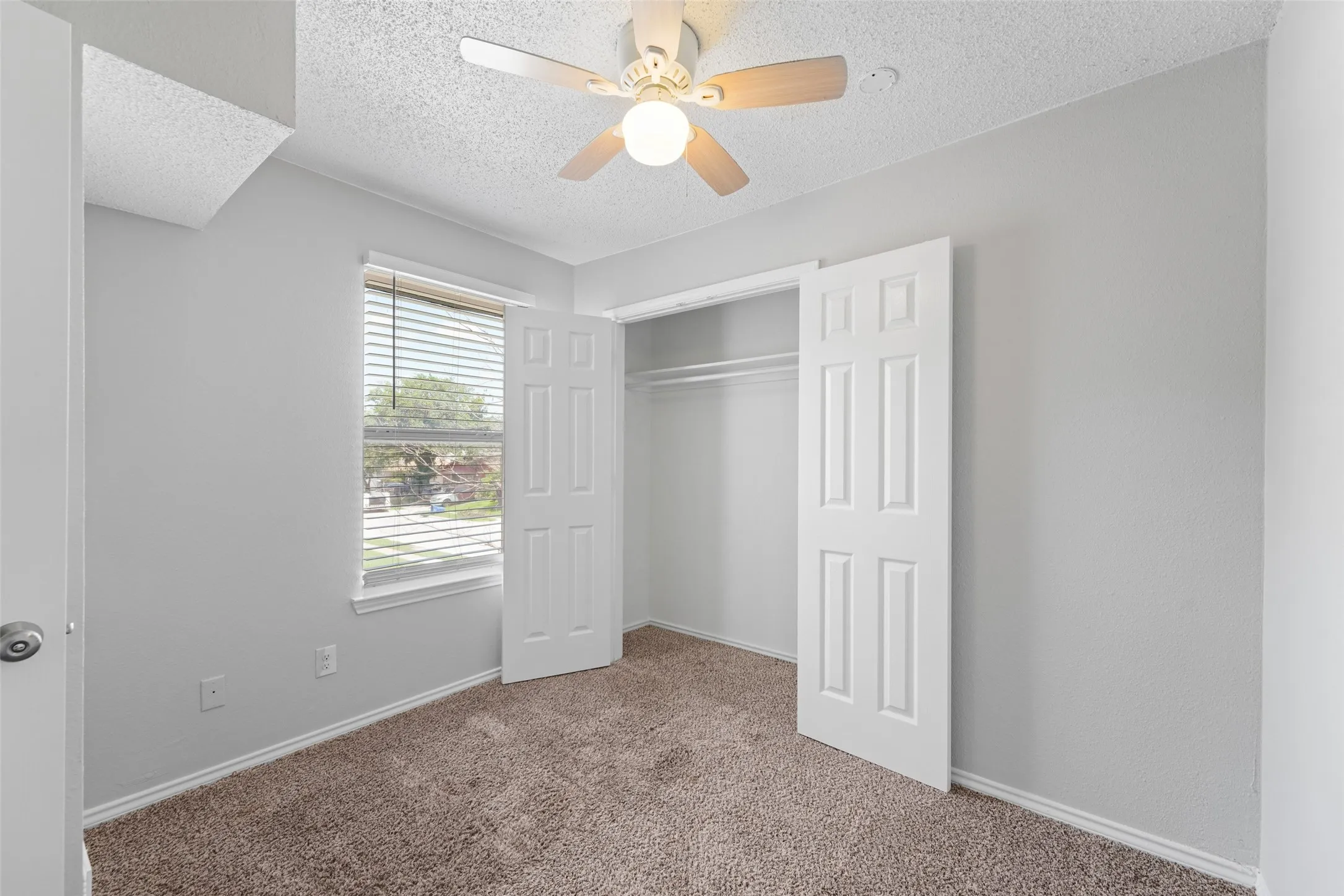 Bedroom featuring neutral wall paint, textured ceiling, brown carpet, and a ceiling fan with light fixture