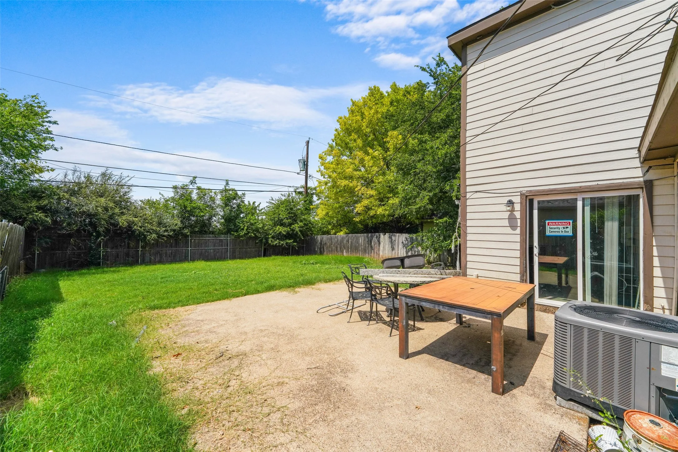 Spacious backyard featuring a concrete patio, expansive lawn, and surrounding wood fencing