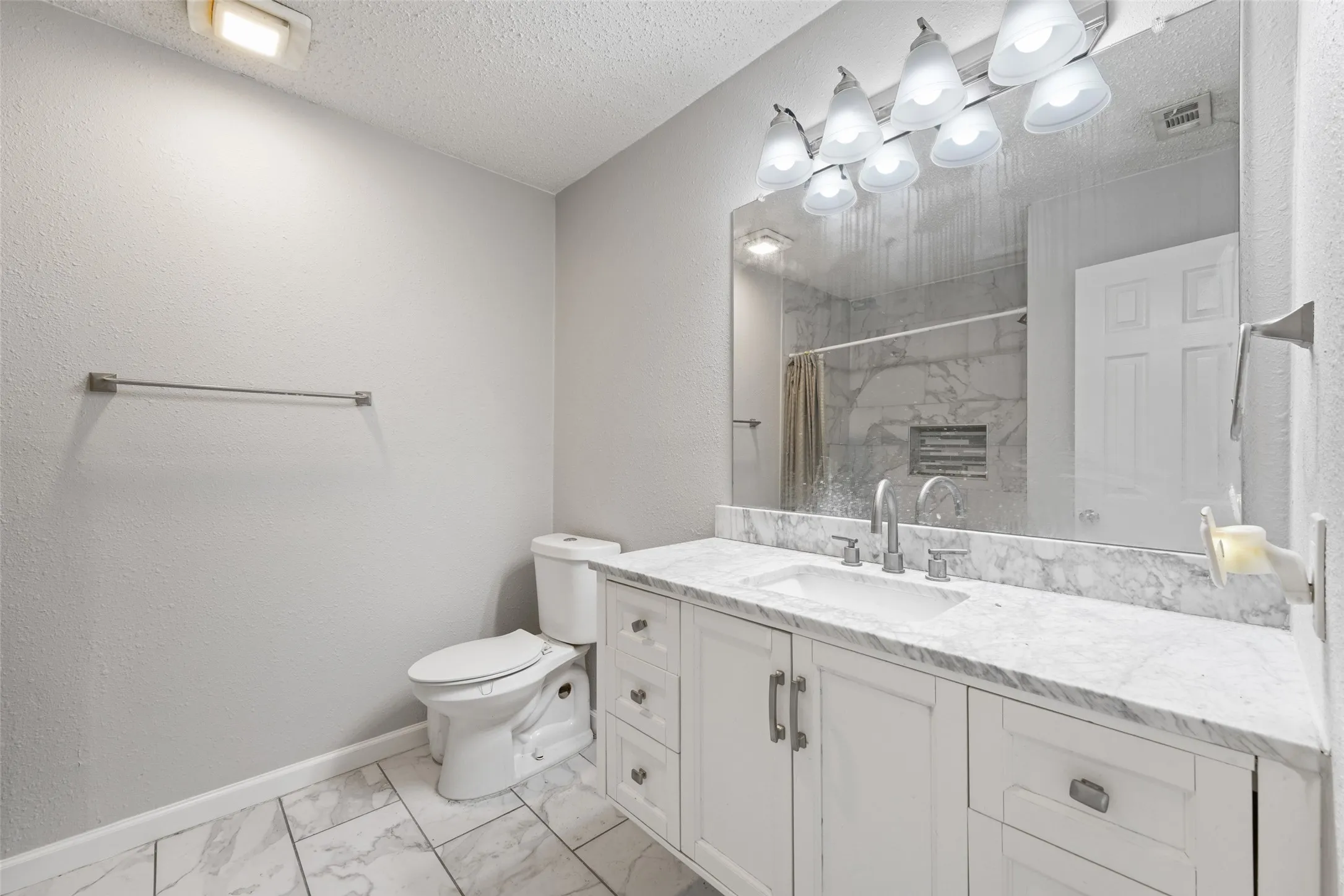 Bathroom featuring a white vanity with a stone countertop, an integrated sink, and brushed nickel hardware
