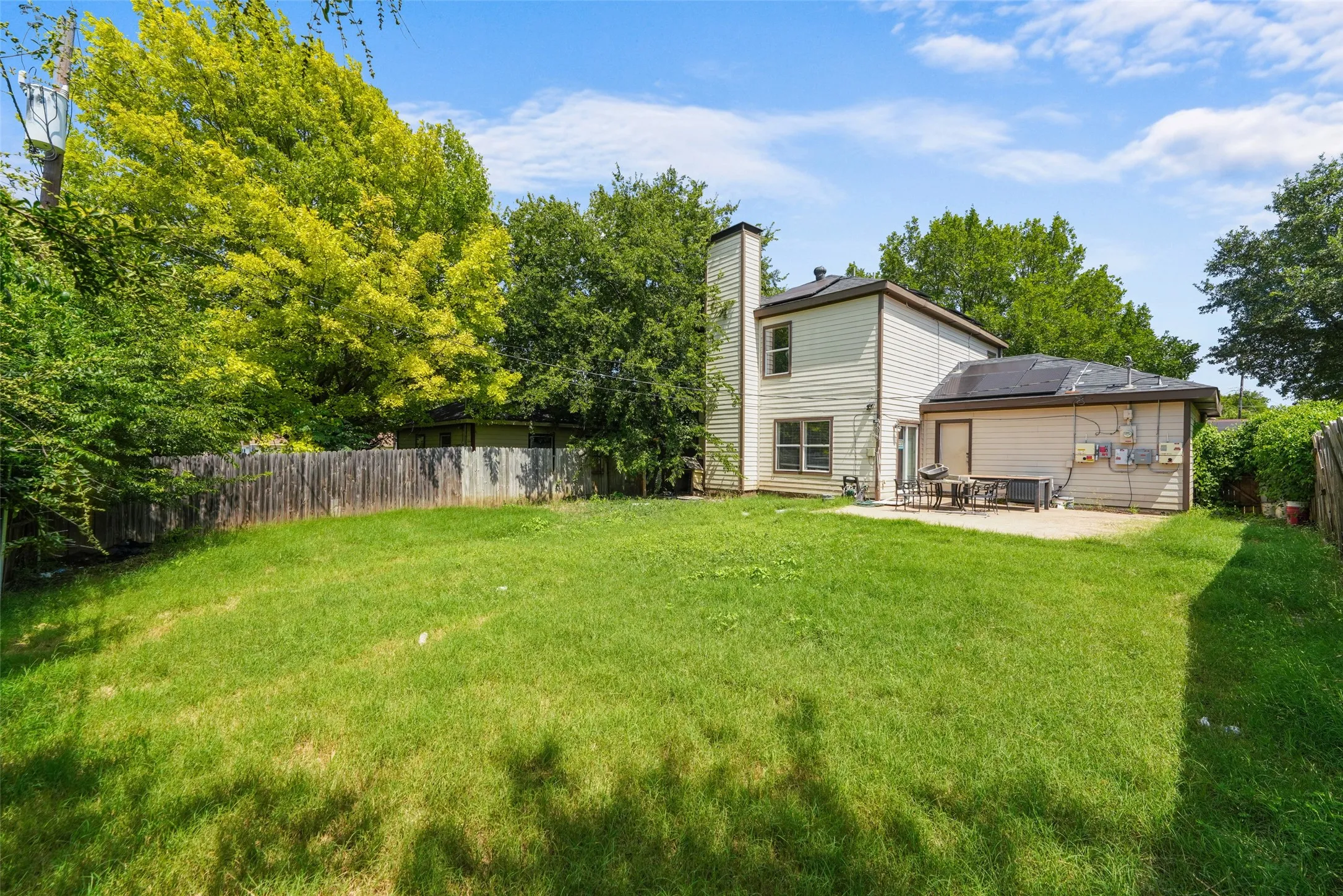 Spacious backyard featuring a large green lawn and a concrete patio