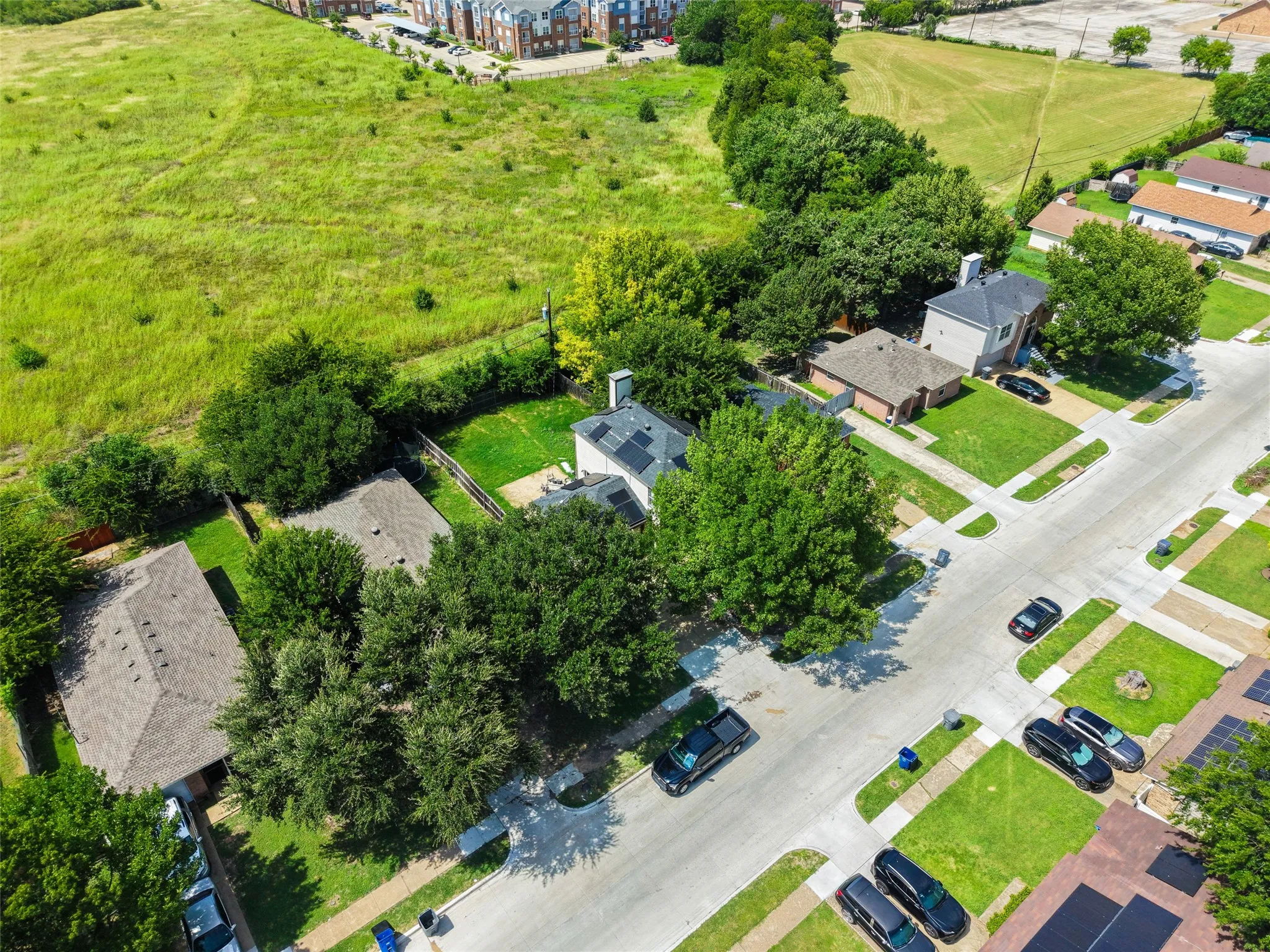 Residential street featuring mature trees, paved sidewalks, and well-maintained lawns
