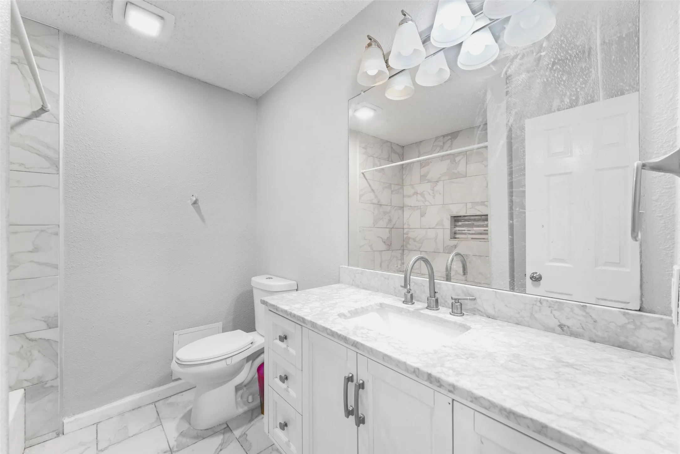 Bathroom featuring a white vanity with shaker-style cabinetry, a white countertop, and a single undermount sink with a brushed nickel faucet