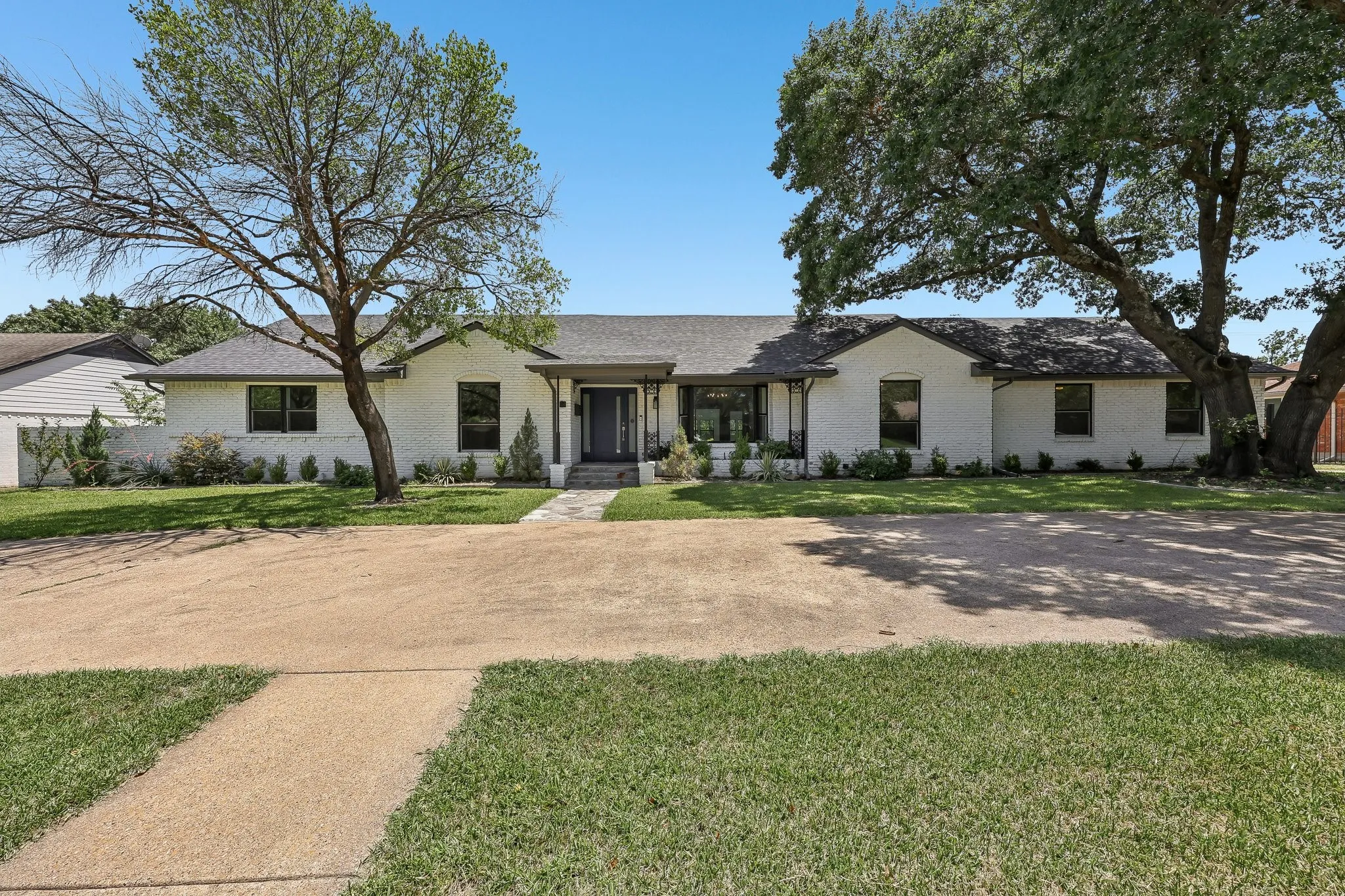 Single-story residence featuring a white brick exterior and a dark-toned shingle roof