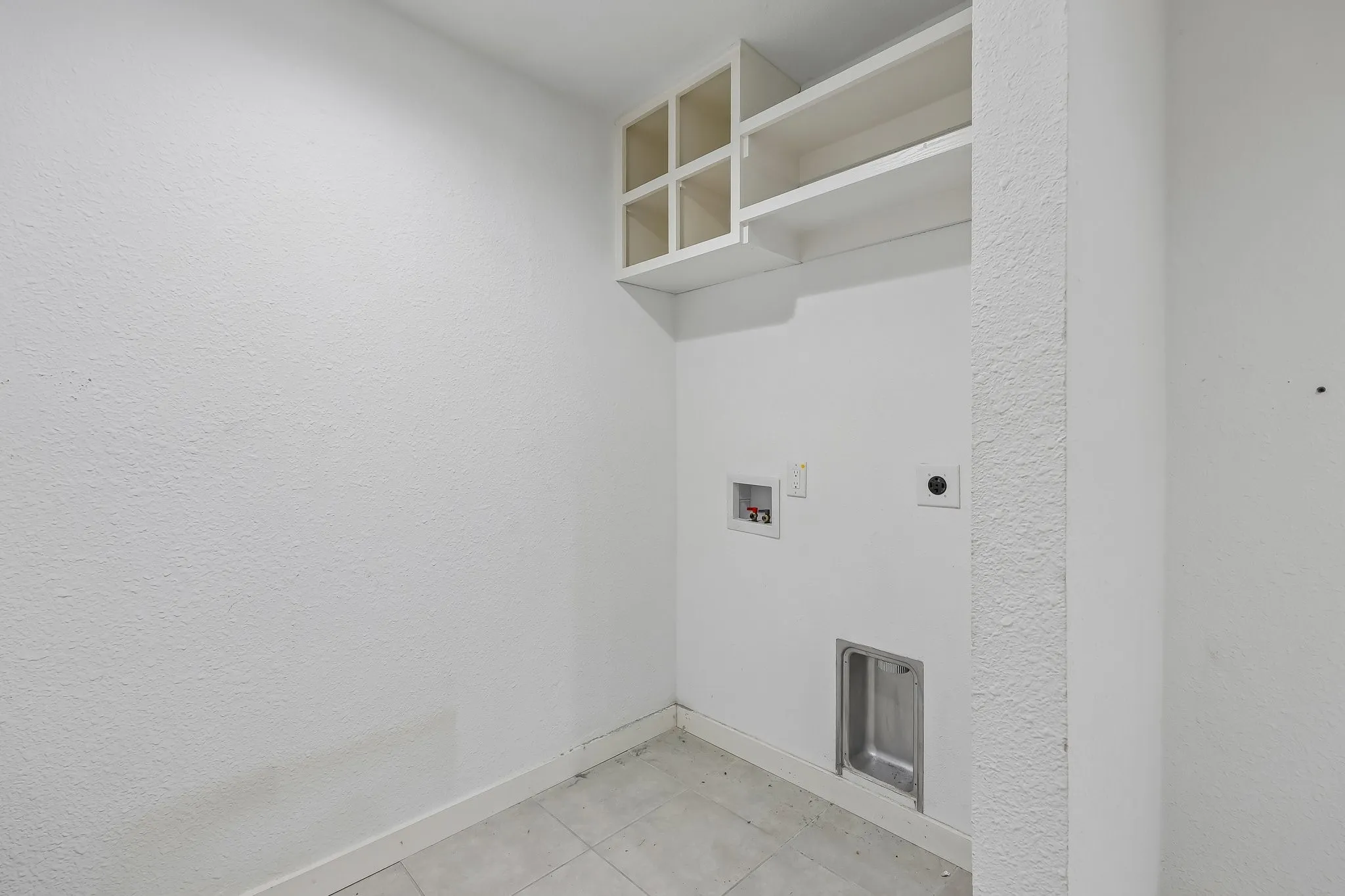 Dedicated utility space featuring tiled flooring and integrated wall cabinetry