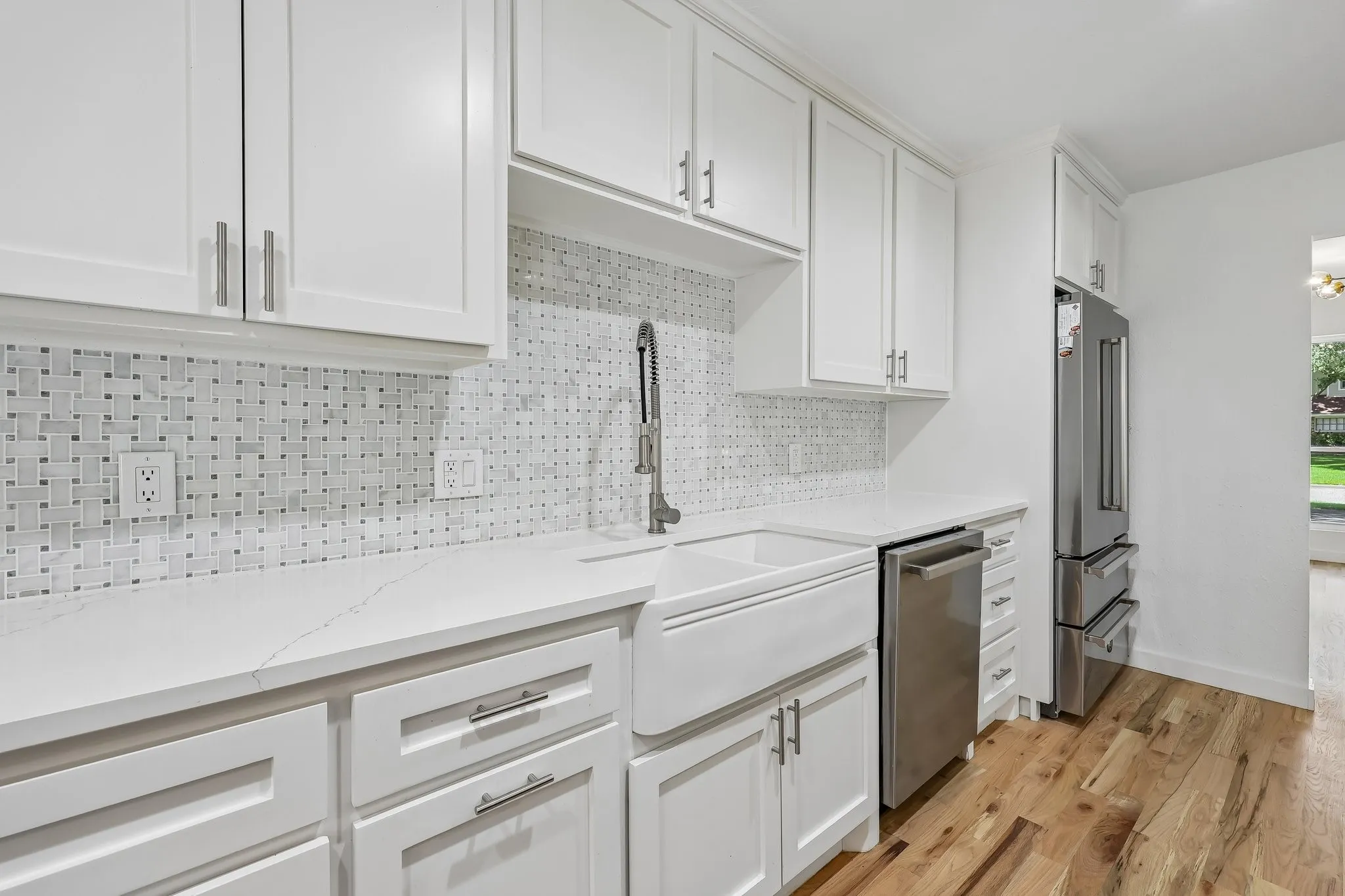 Kitchen featuring white shaker cabinetry, patterned tile backsplash, white countertop, stainless steel appliances, and wood-finish flooring