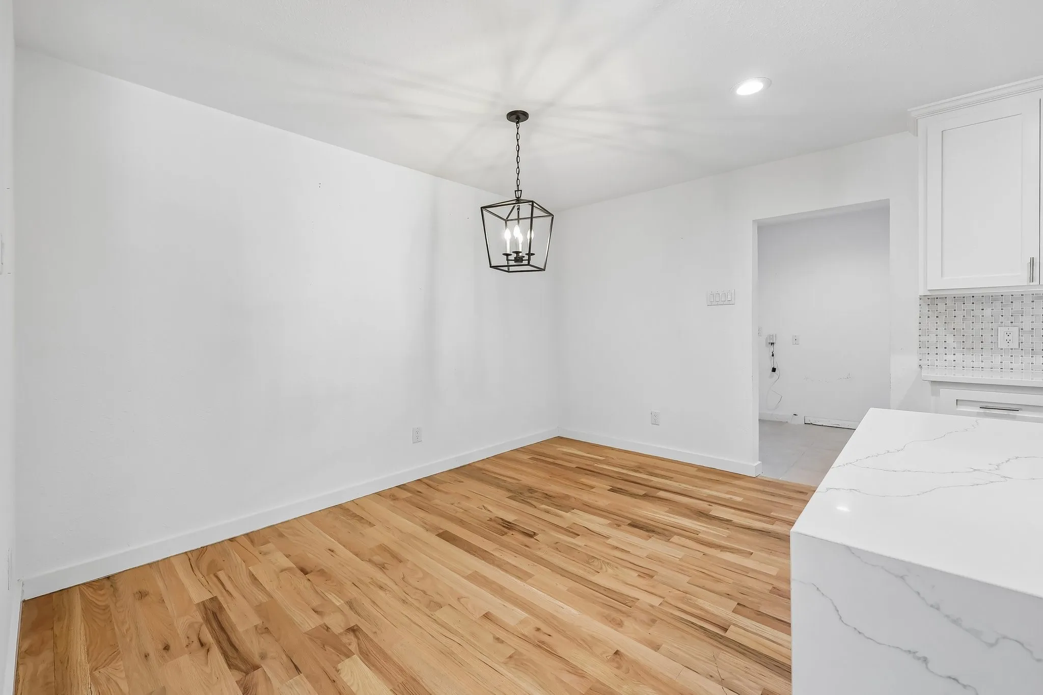 Dining area with wood-finish flooring, a black geometric chandelier, and white baseboards