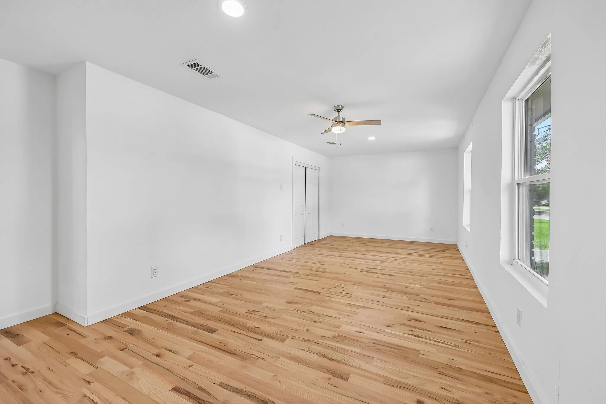 Spacious room with natural wood-finish flooring