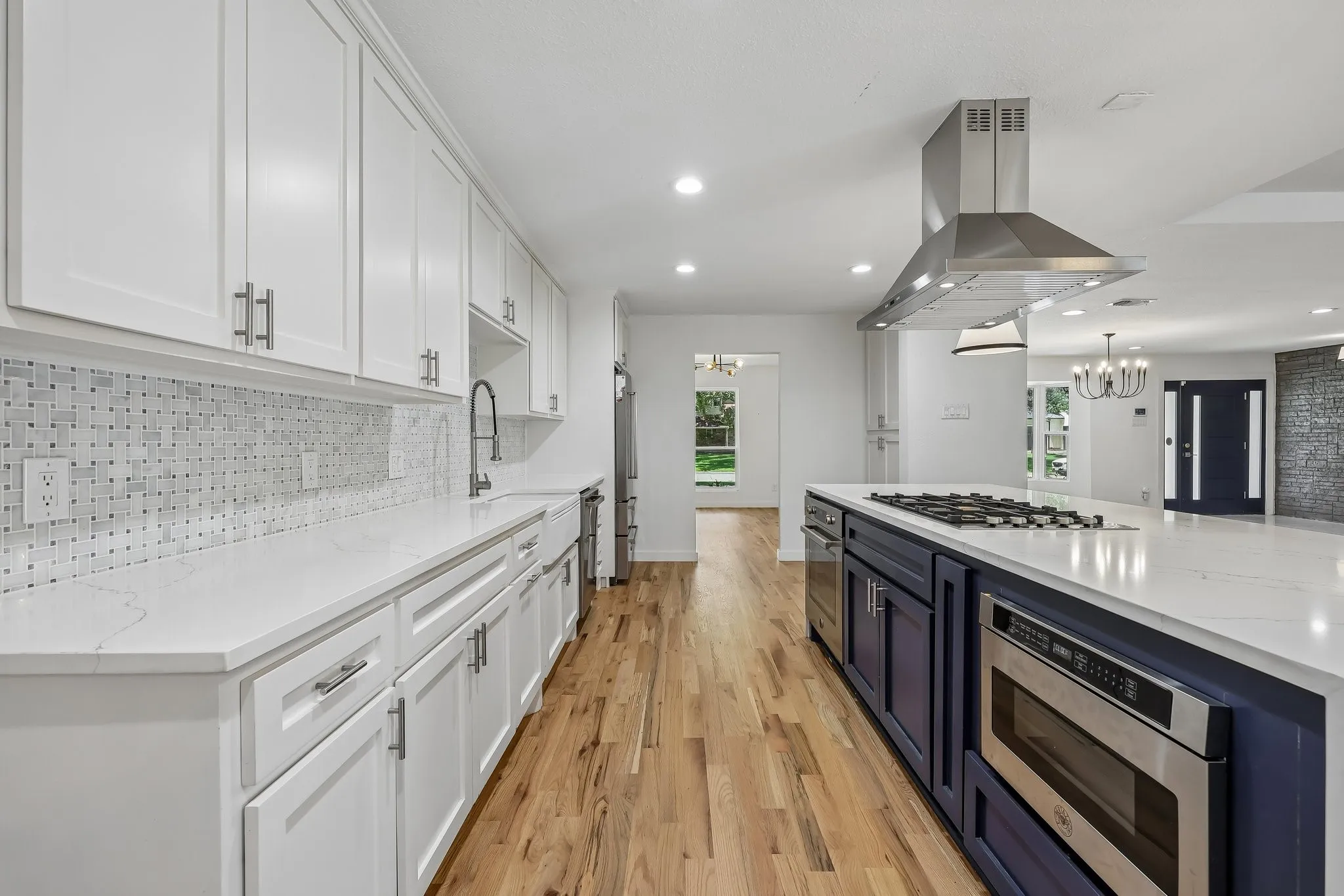 Modern kitchen featuring white shaker cabinetry, light wood-finish flooring, a patterned tile backsplash, and white countertops