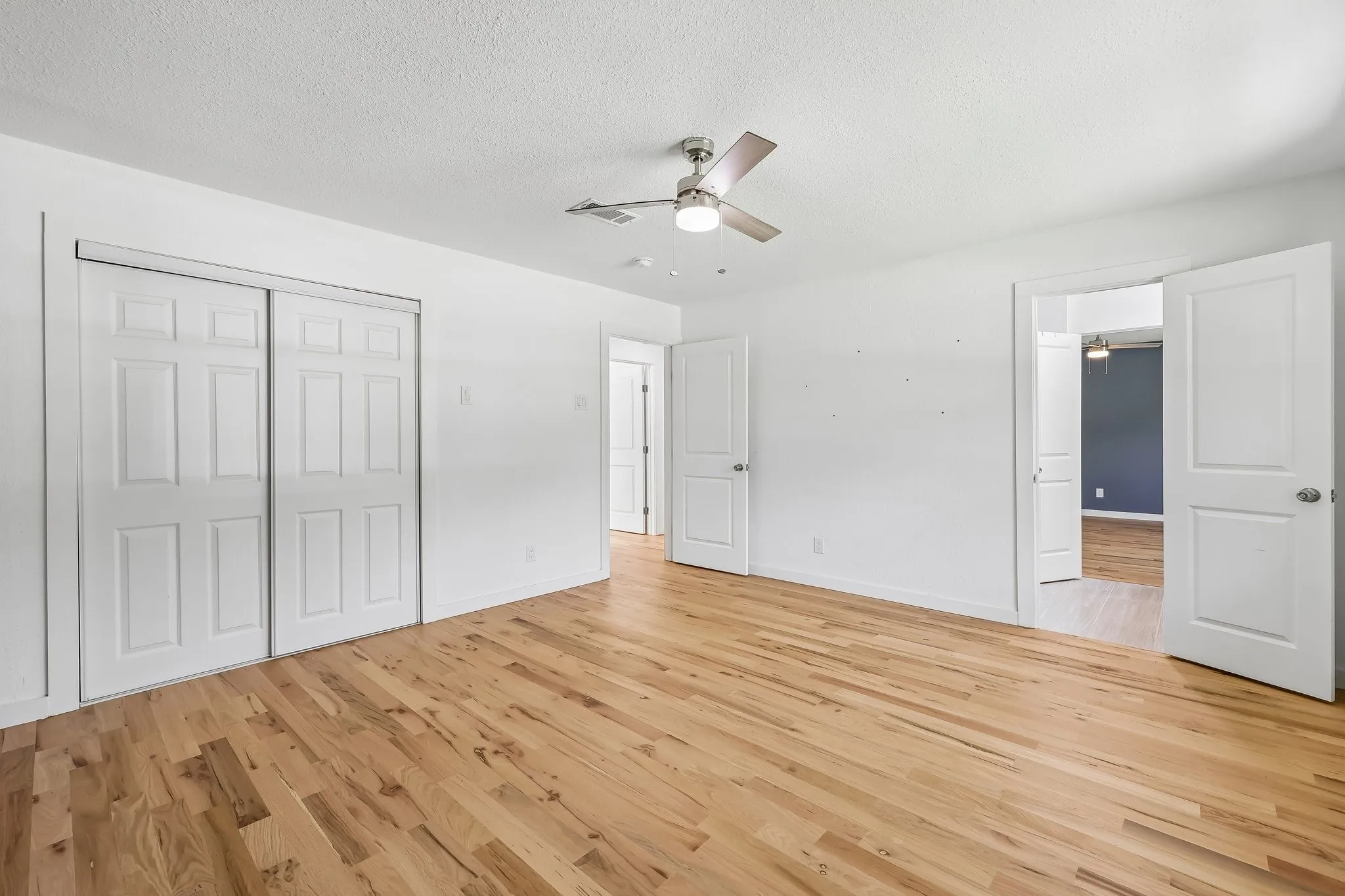 Spacious room featuring light wood-finish flooring and bright white walls