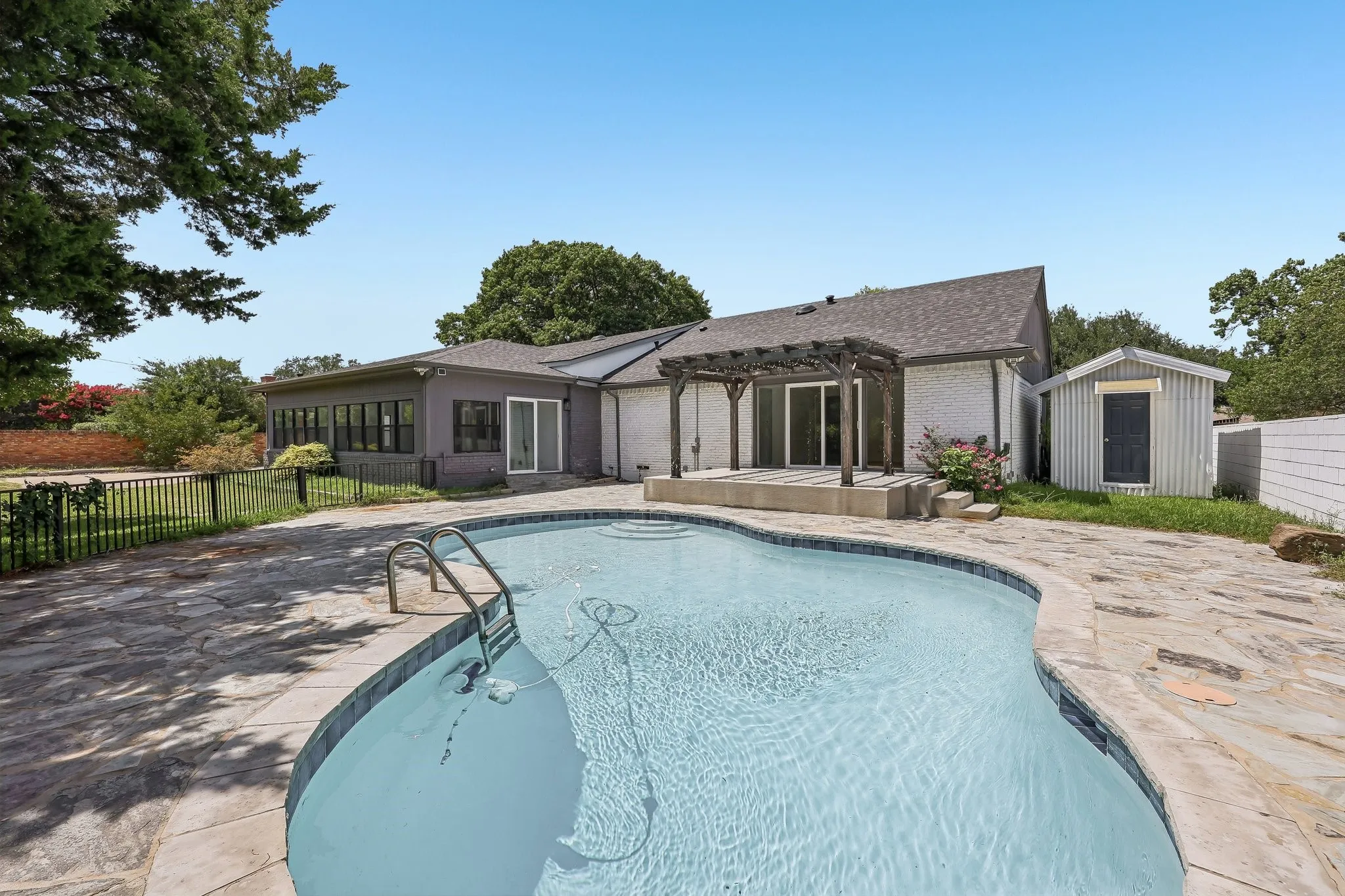 Curved in-ground pool surrounded by flagstone patio