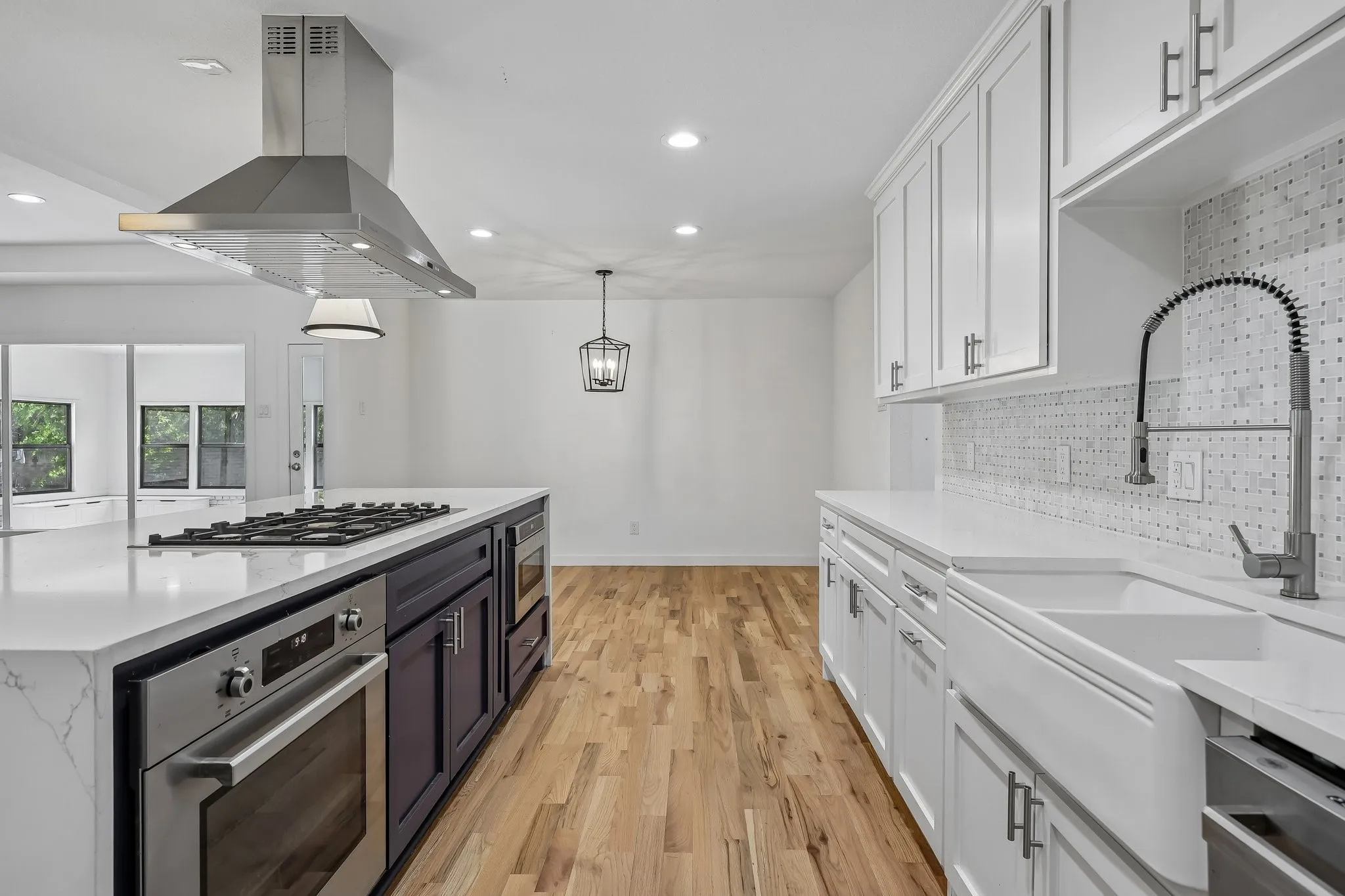 Modern kitchen featuring white shaker cabinetry, white countertops, stainless steel appliances, a center island with a gas range, and wood-finish flooring