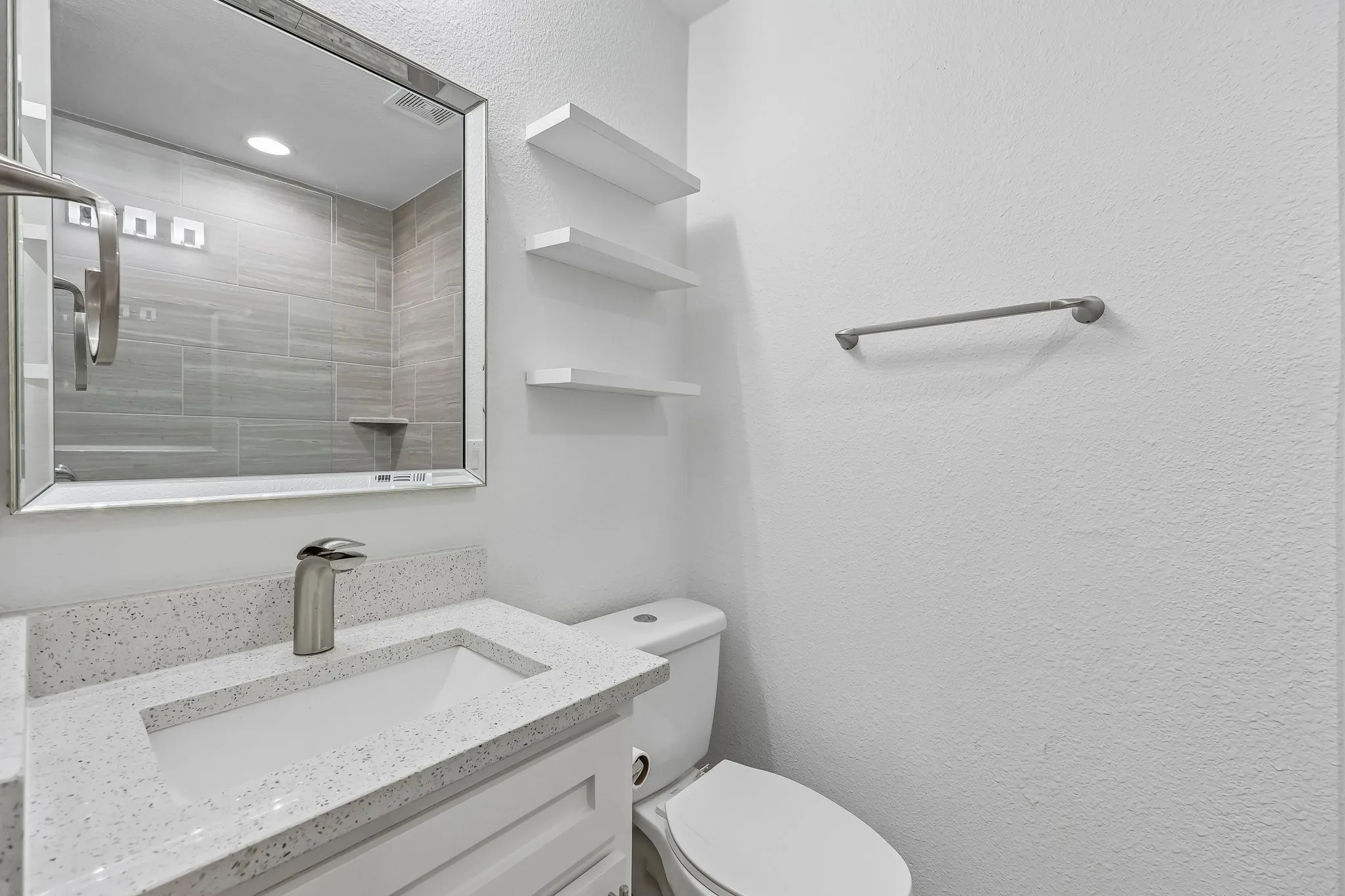 Modern bathroom vanity featuring a quartz countertop, integrated sink, and brushed nickel faucet