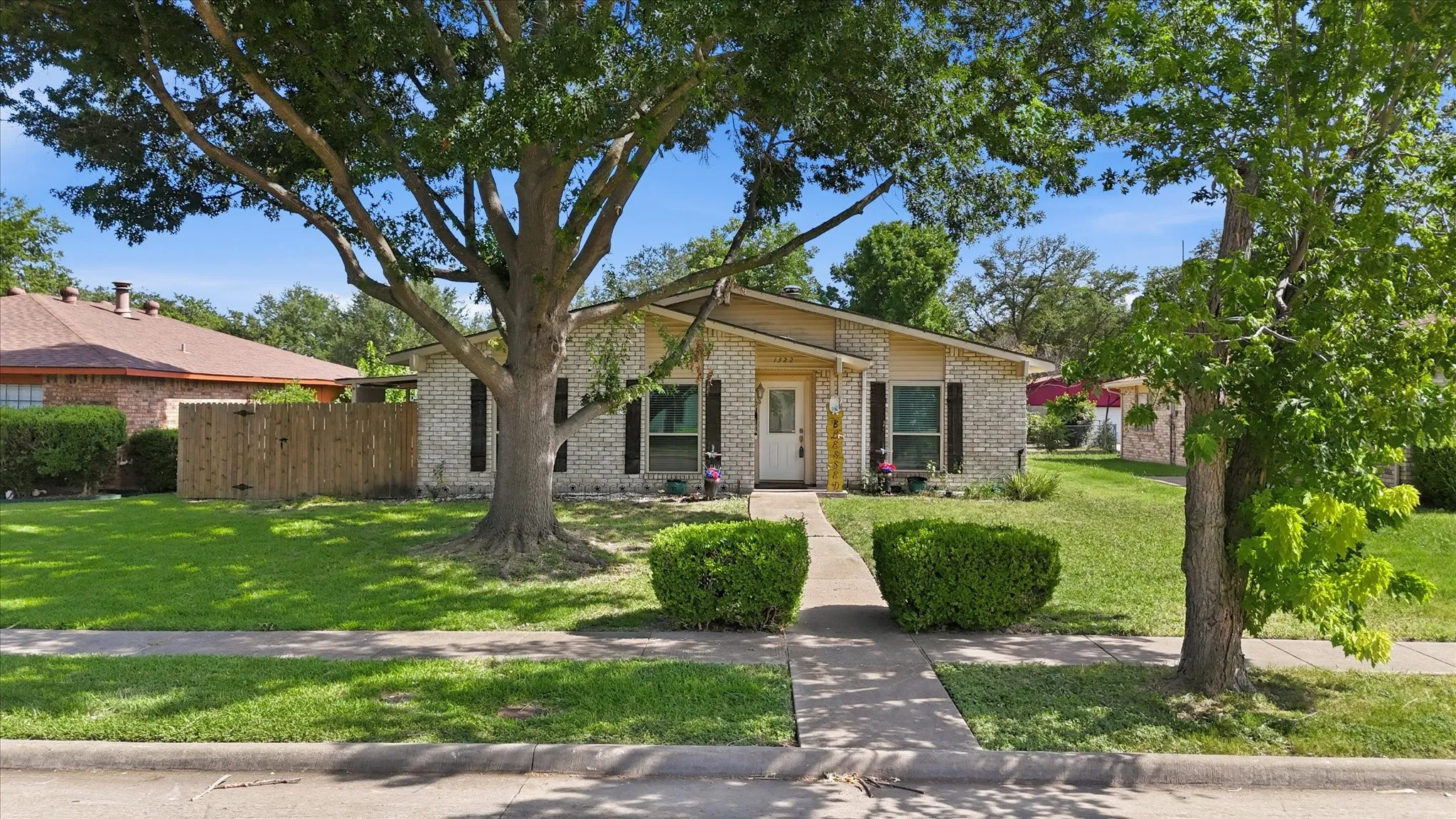 Craftsman traditional style home featuring large fully fenced grassy yard, mature trees, rear covered patio  in Garland TX. Choice of schools.